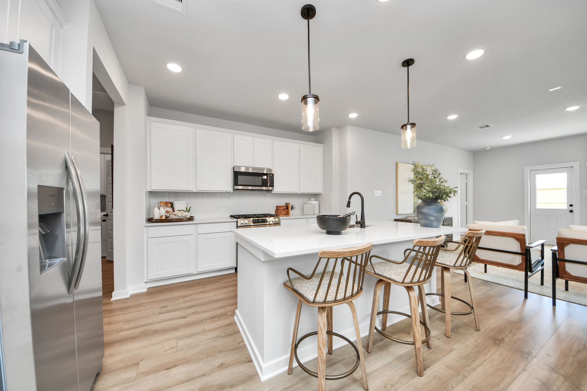 Modern kitchen with white cabinets, quartz island, and bar seating at Robins Landing in Houston by Davidson Homes.