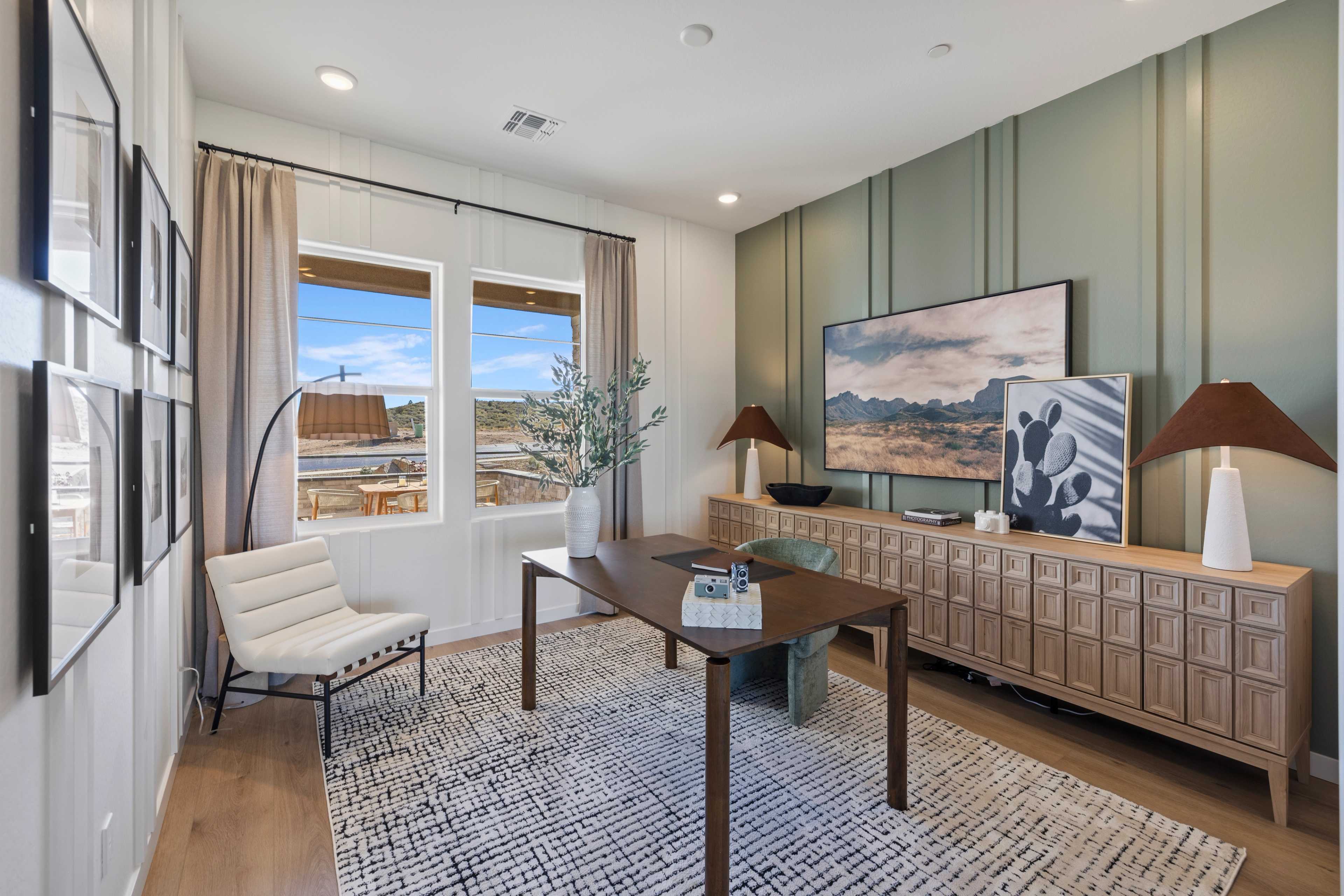 Contemporary home office in Hidden Hills Prescott AZ by Davidson Homes with desert view windows, sage green accent wall, and wooden desk