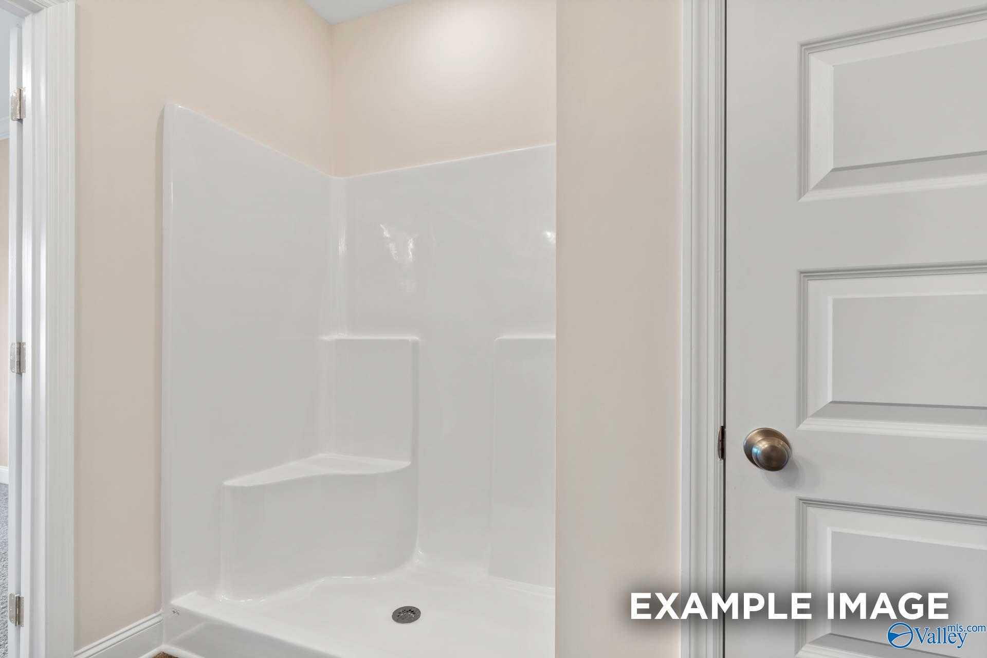 Modern white corner shower with built-in bench in secondary bath of The Asheville 3-bed home by Davidson Homes, Arab, Alabama
