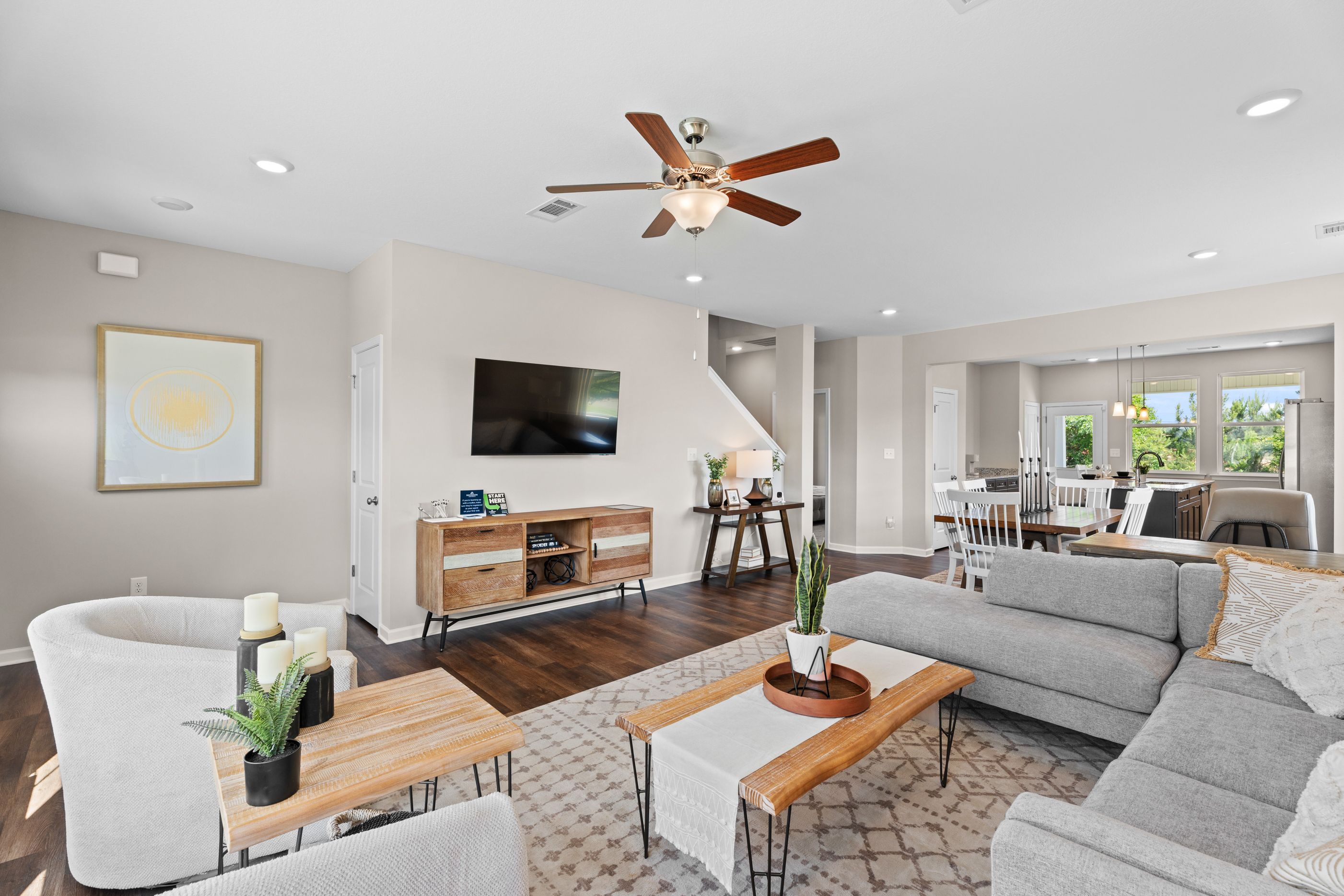 Spacious open-concept living room in Ivy Glen Perry Georgia with hardwood floors gray sectional sofa large windows and ceiling fan