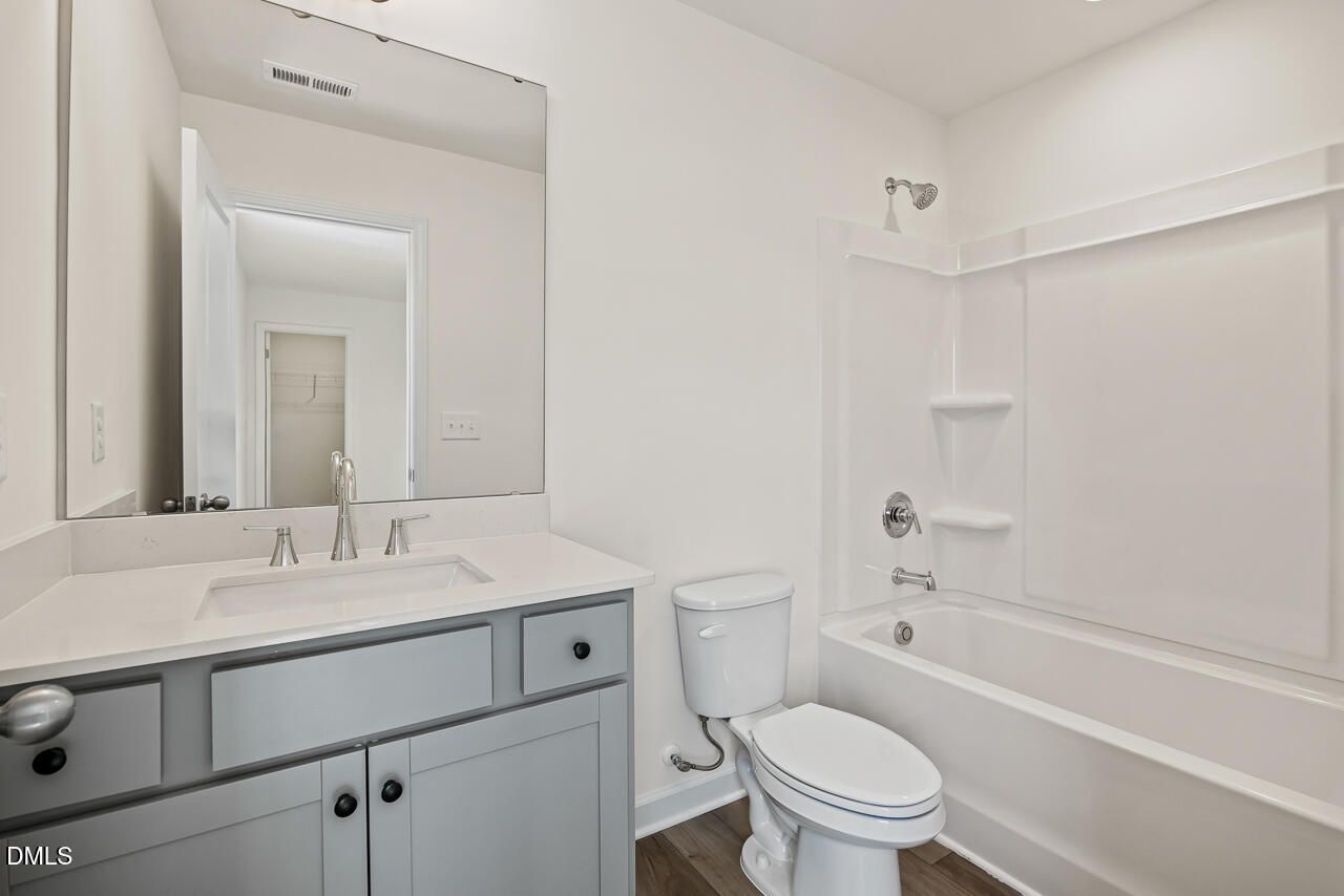 Bright full bathroom with gray vanity, white quartz countertop, and tub-shower combo in Davidson Homes The Hickory II B, Lillington