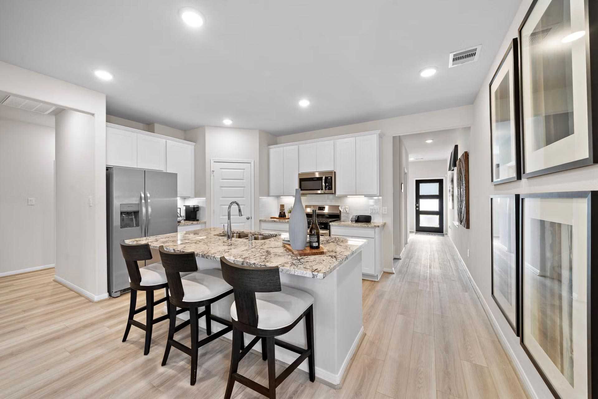 Spacious modern kitchen at Saddle Creek Ranch in Cibolo Texas with white cabinets granite island bar seating and stainless appliances