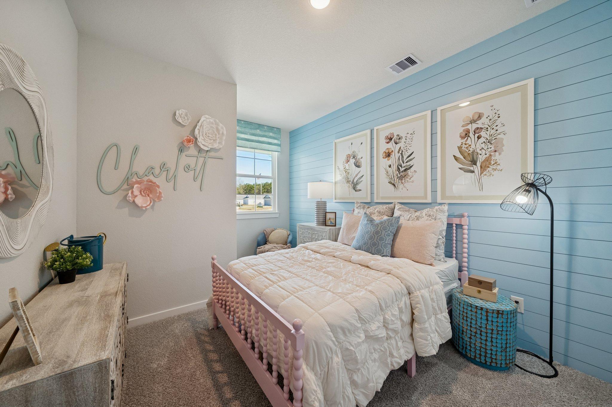 Charming girl's bedroom in Spring Branch Crossing, Conroe, Texas with pink bed, blue shiplap walls, floral art by Davidson Homes