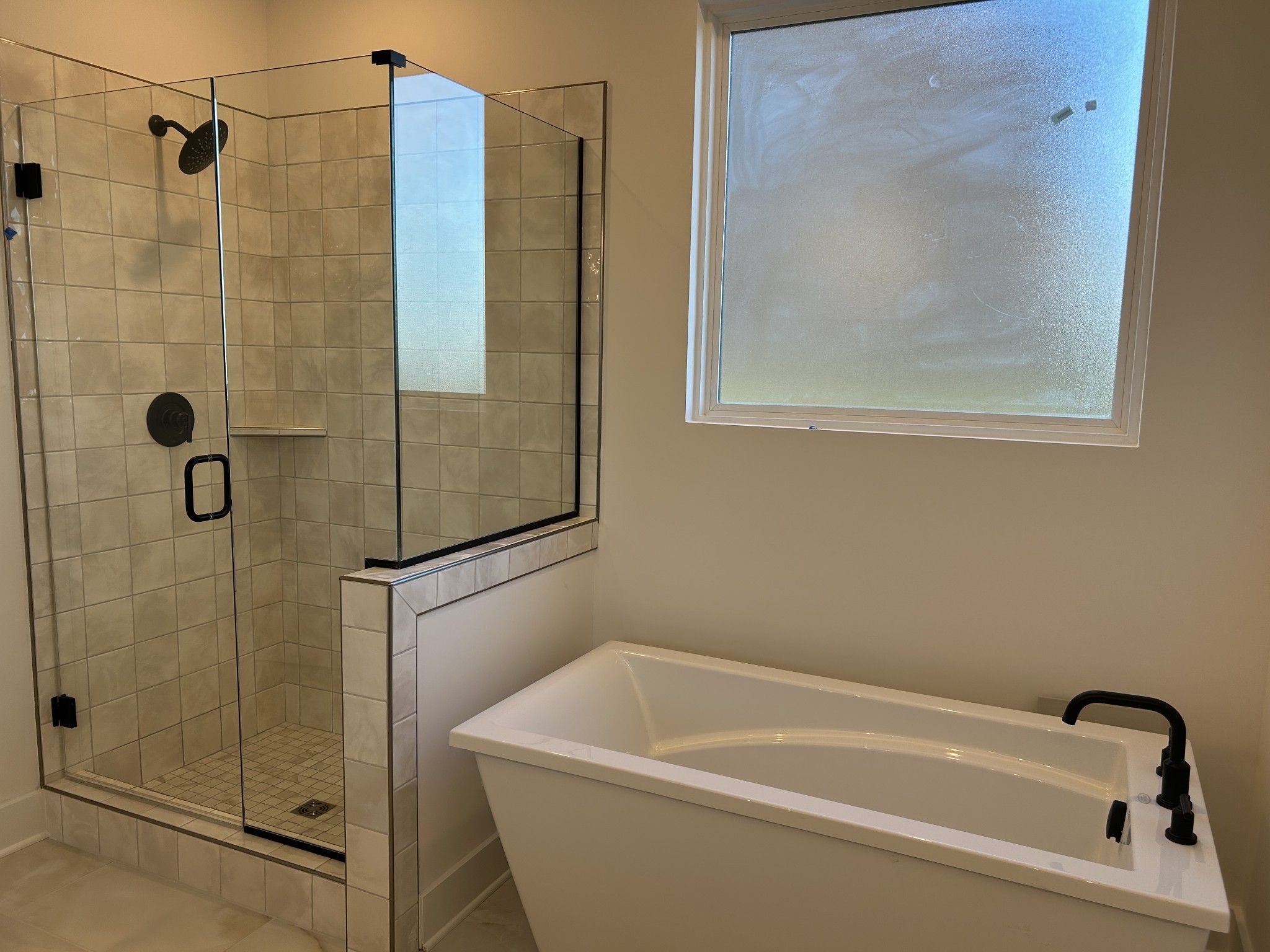 Luxurious master bathroom with frameless glass shower, freestanding tub, and frosted window in The Ridgeport F, Mt. Juliet, TN