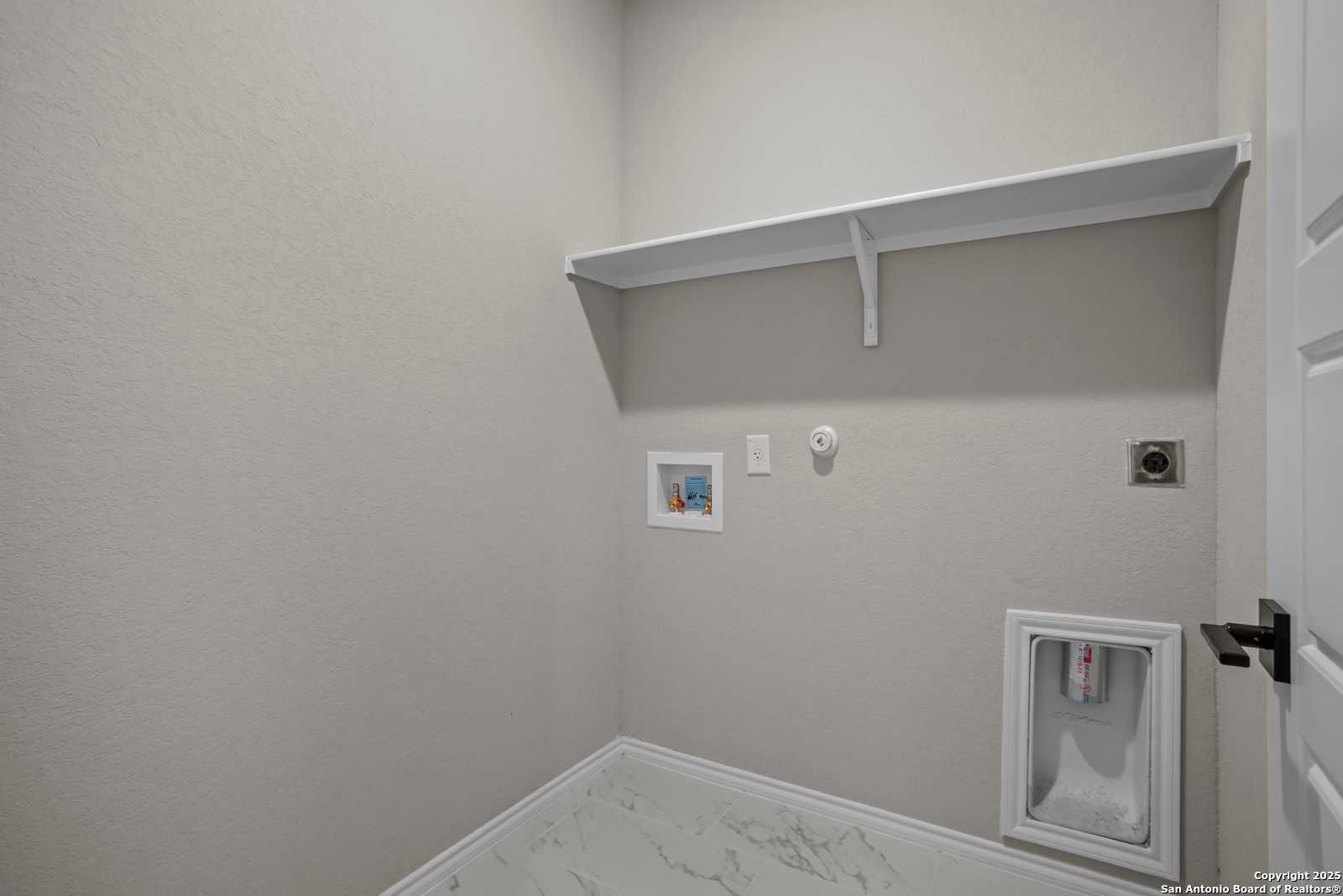 Modern laundry room with utility sink, white floating shelf, and beige walls in The Asheville E by Davidson Homes, Converse, Texas