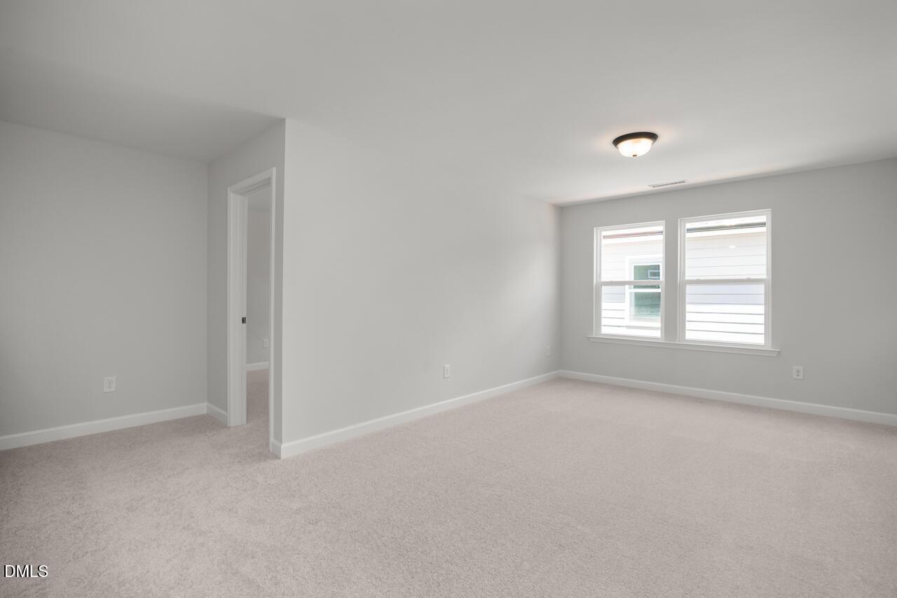 Spacious primary bedroom with neutral carpet and natural light in The Birch II E floor plan at Sage on North Main.