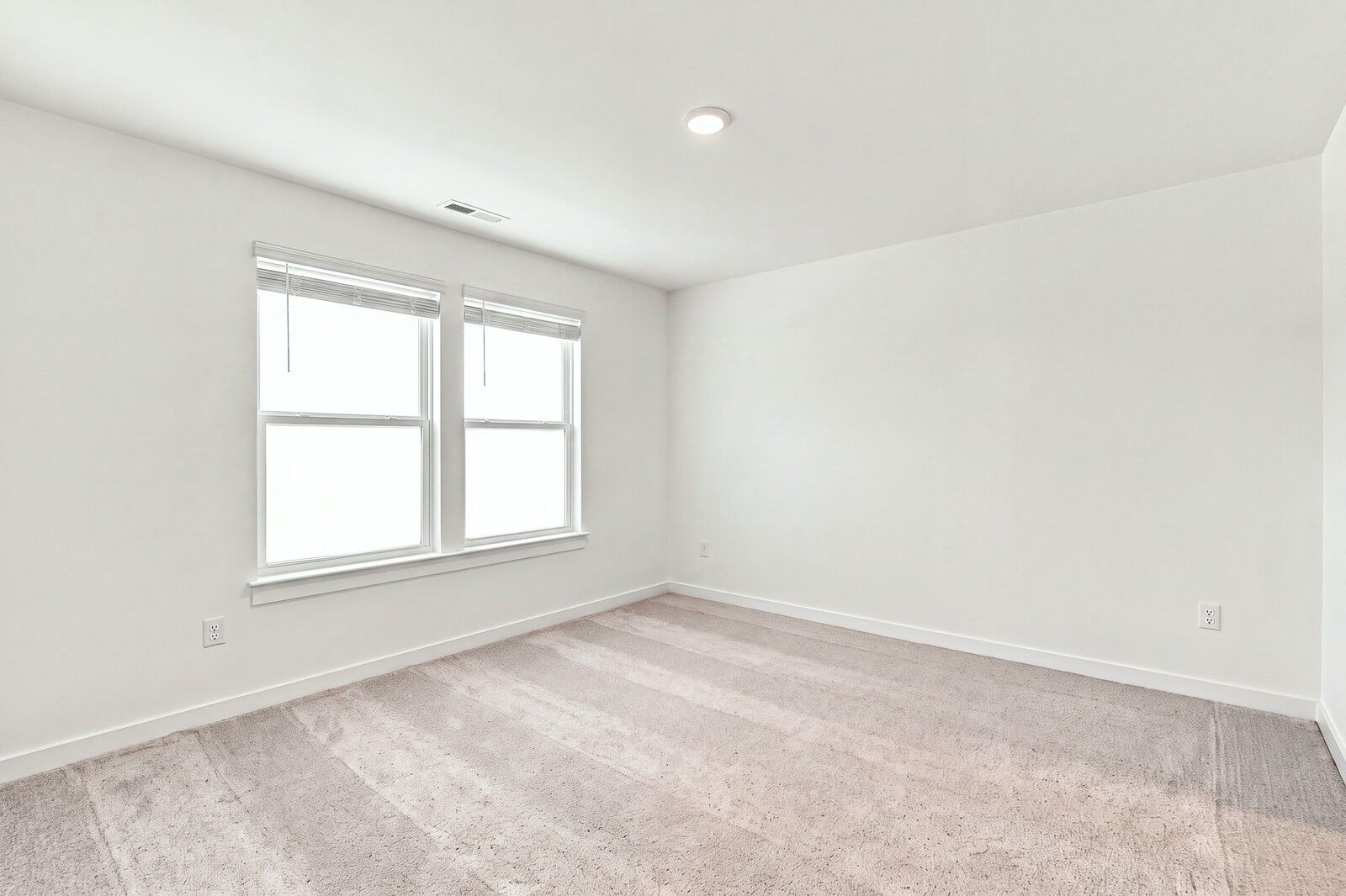 Bright empty bedroom with carpet and dual windows in Davidson Homes The Willow C plan at Woods Crossing, Gallatin, Tennessee