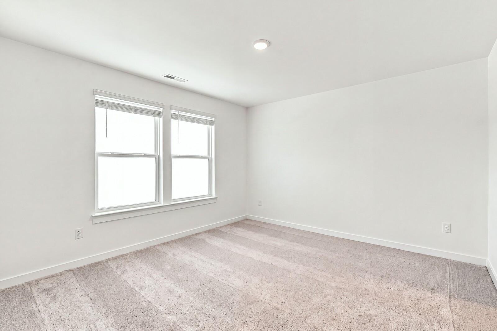 Bright empty bedroom with carpet and dual windows in Davidson Homes The Willow C plan at Woods Crossing, Gallatin, Tennessee