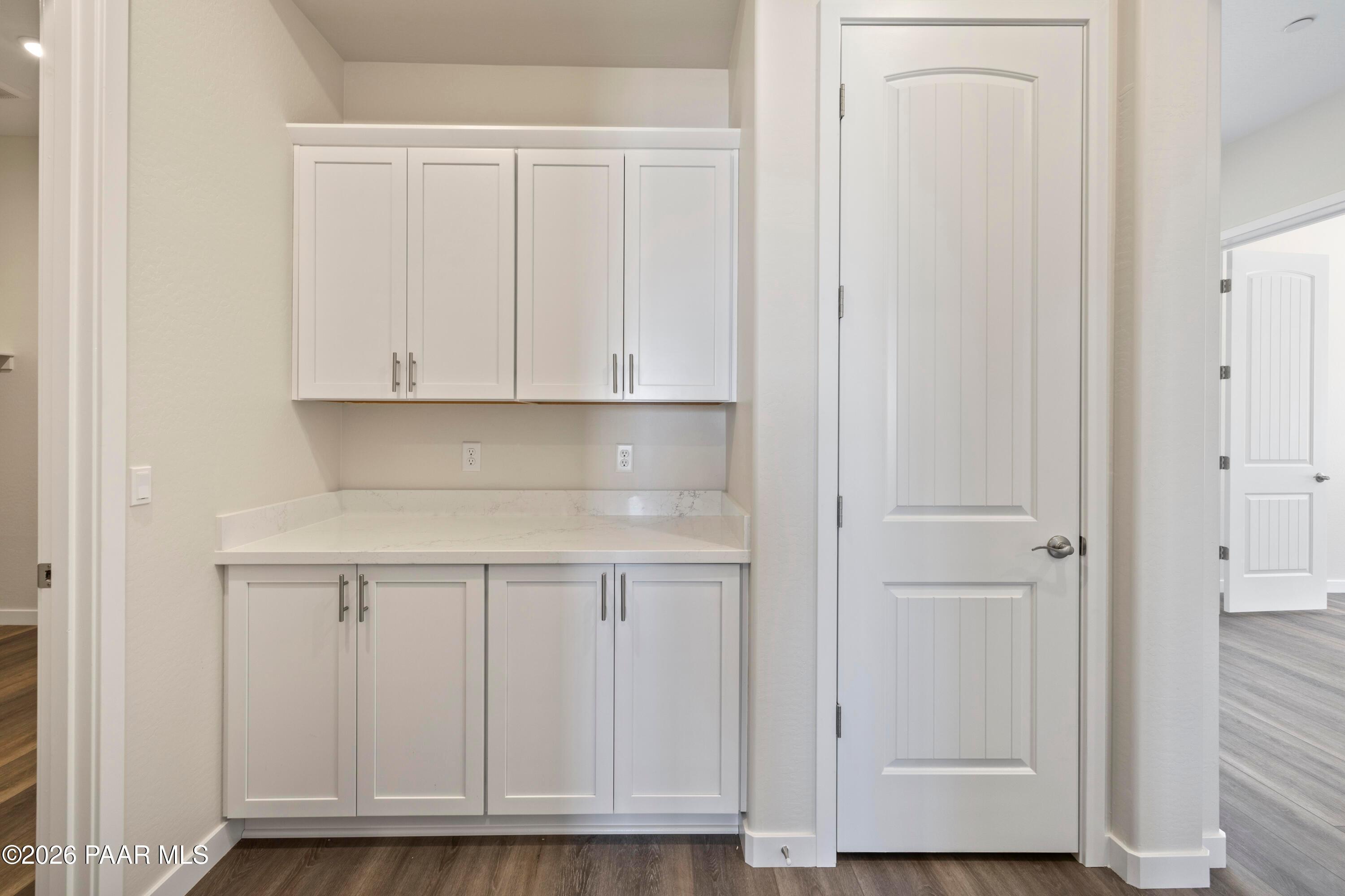 Bright laundry room with white shaker cabinets, countertop, and adjacent door in Davidson Homes The Soleil E, Prescott, AZ
