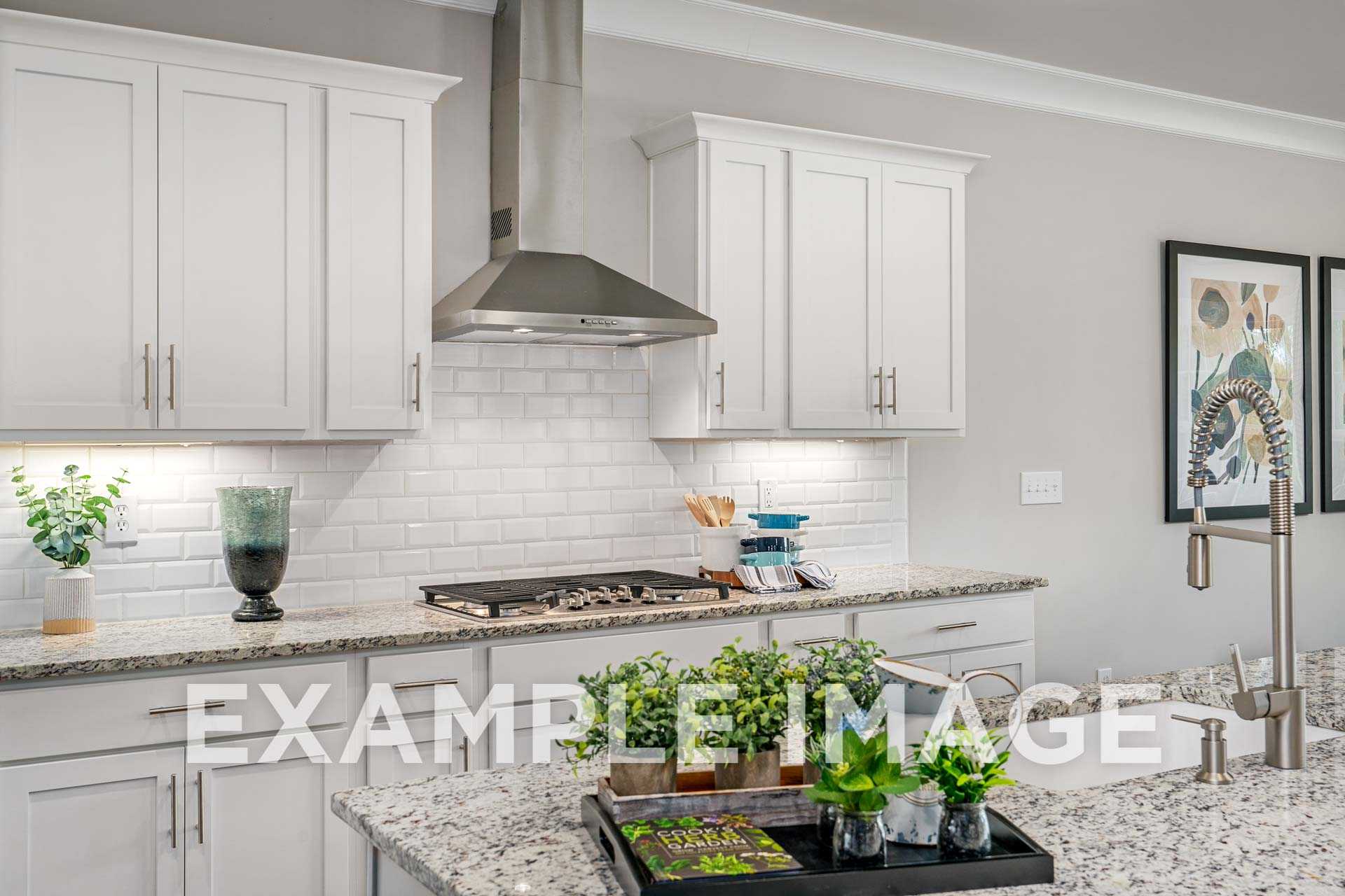 Spacious modern kitchen in The Harrison with white shaker cabinets, granite island, subway tile backsplash, and stainless steel hood