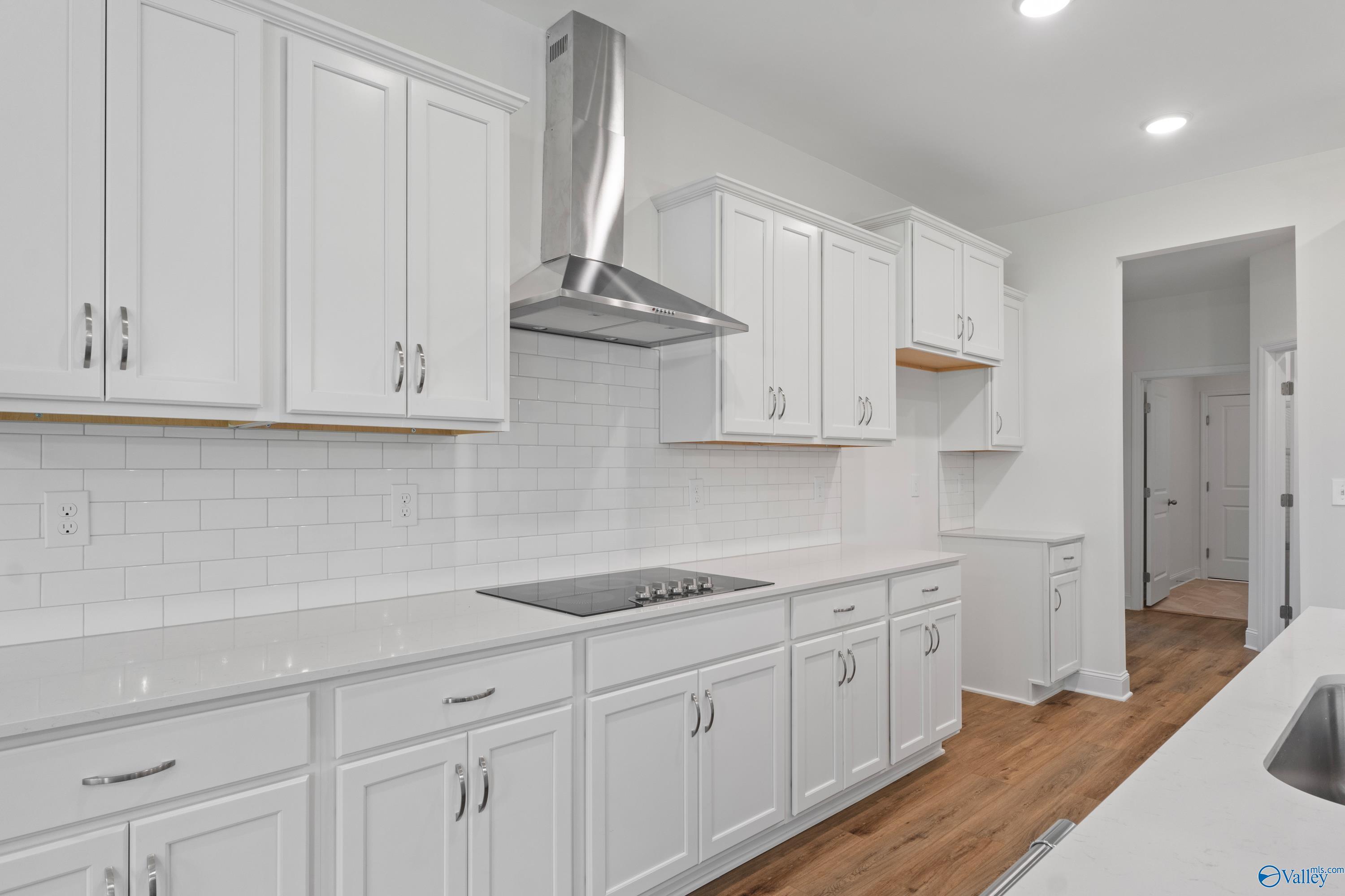 Bright white kitchen with shaker cabinets, quartz counters, stainless hood, subway tile backsplash in Davidson Homes The Oxford, Harvest AL