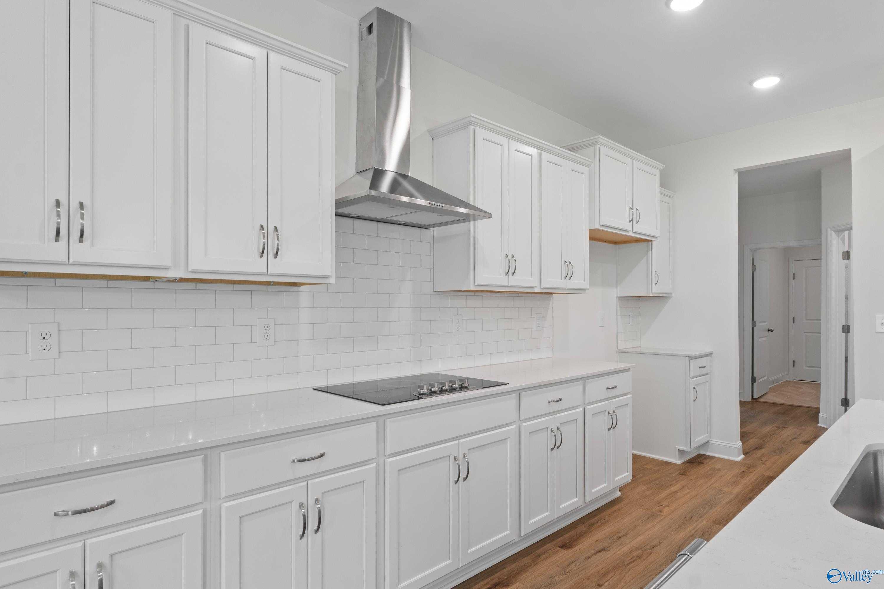 Bright white kitchen with shaker cabinets, quartz counters, stainless hood, subway tile backsplash in Davidson Homes The Oxford, Harvest AL