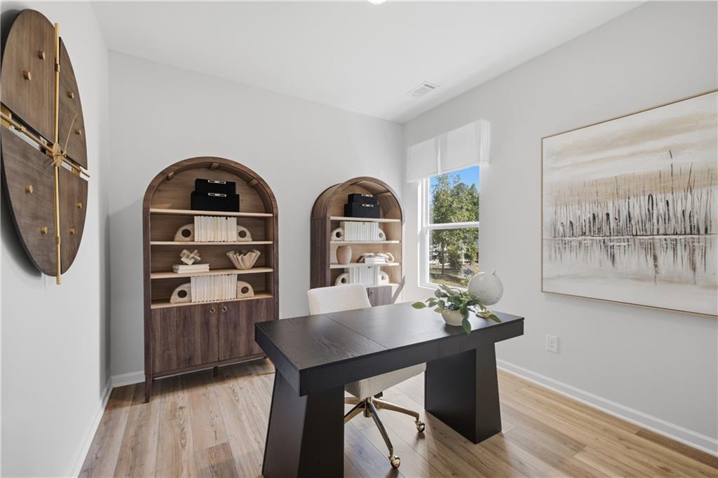 Bright home office with dark wood desk, arched bookshelves, and hardwood floors in The Sinclair B, Greene Farm, Cartersville, Georgia