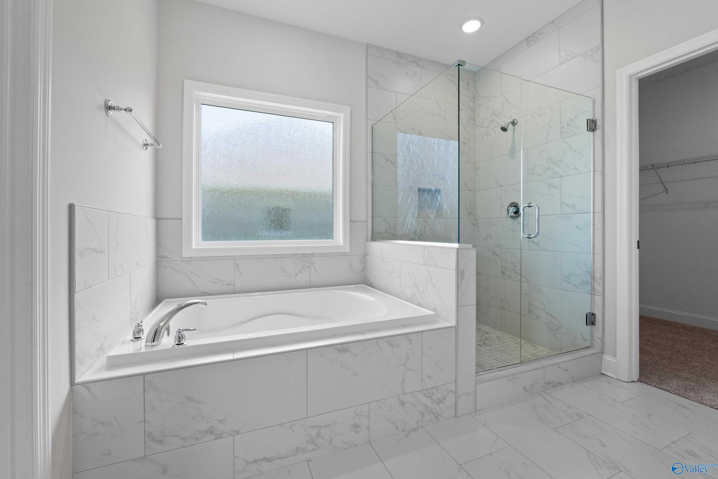 Modern master bathroom with glass shower, freestanding tub, white subway tile in The Harrison B by Davidson Homes, Meridianville, Alabama