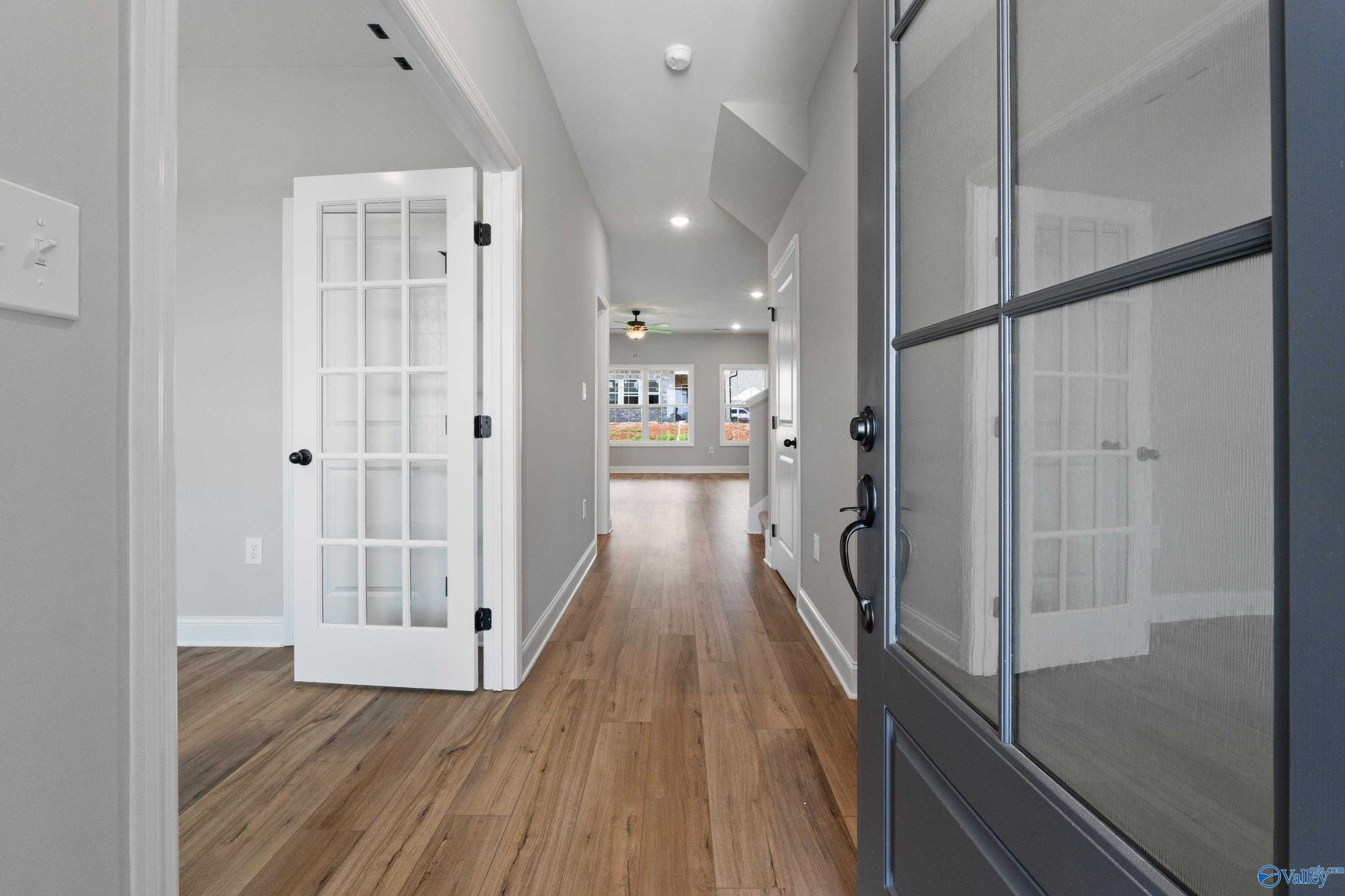 Elegant entry hallway with hardwood floors, glass French doors, and modern front door in Davidson Homes The Rockford with Bonus, Toney AL