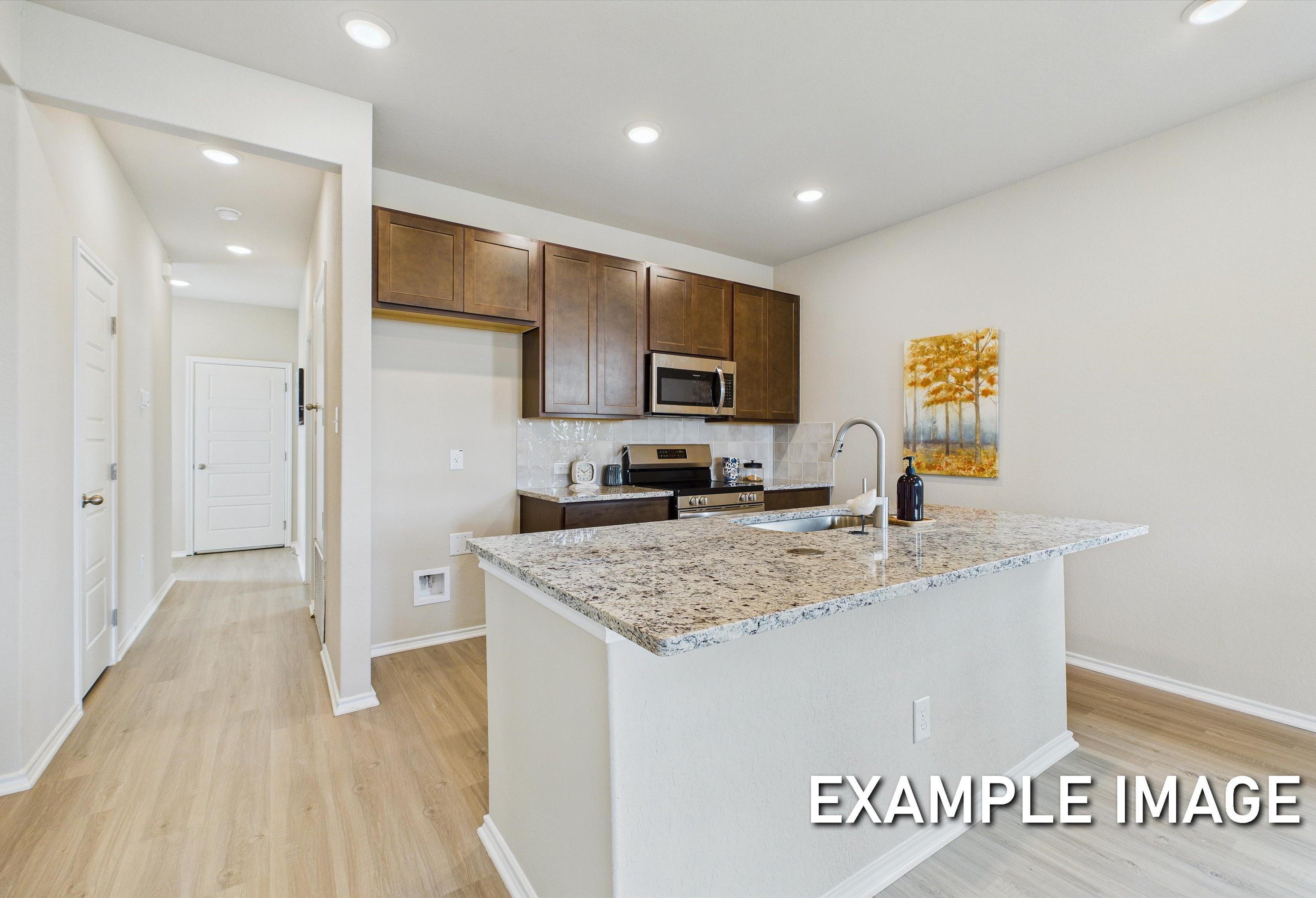 Modern kitchen in The Corral featuring granite countertops, dark wood cabinetry, and a central island in San Antonio, TX.
