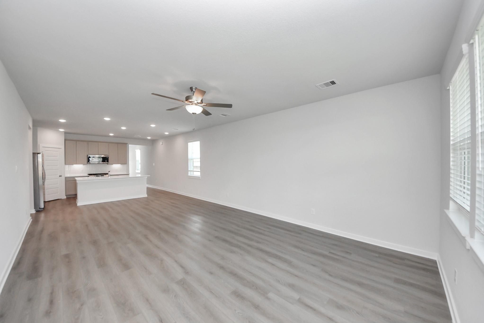 Open-concept living room and kitchen with vinyl plank flooring and ceiling fan in The San Marcos E by Davidson Homes, Beasley