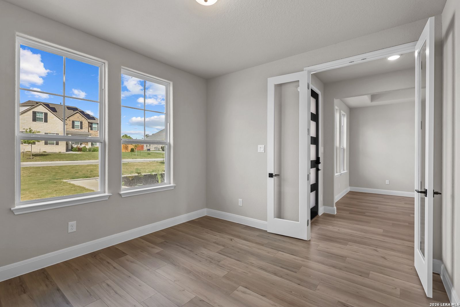Bright room with large windows and wood-look flooring, glass French doors, in Davidson Homes The Foster E, Potranco Oaks, Castroville