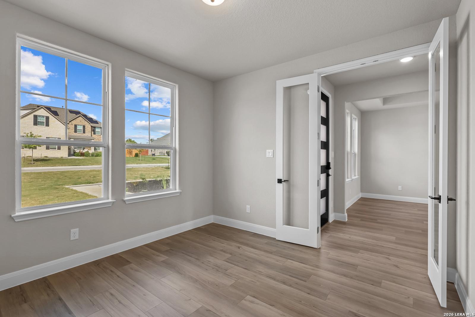 Bright room with large windows and wood-look flooring, glass French doors, in Davidson Homes The Foster E, Potranco Oaks, Castroville