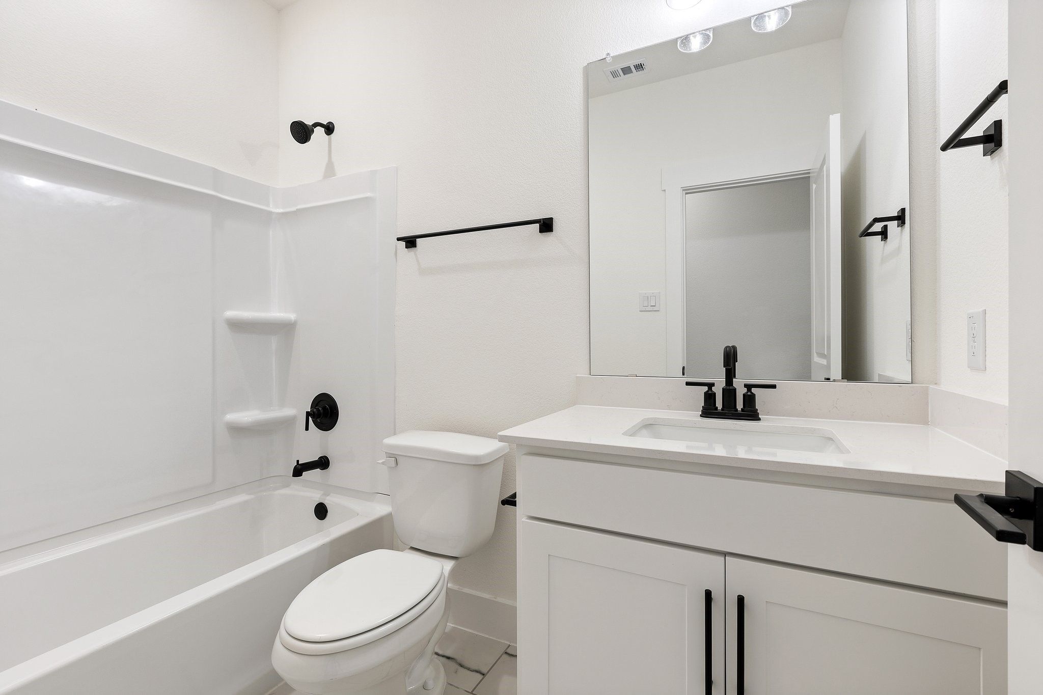 Modern bathroom with white vanity, quartz countertop, and matte black fixtures in The Rockford C plan, Josephine, Texas.