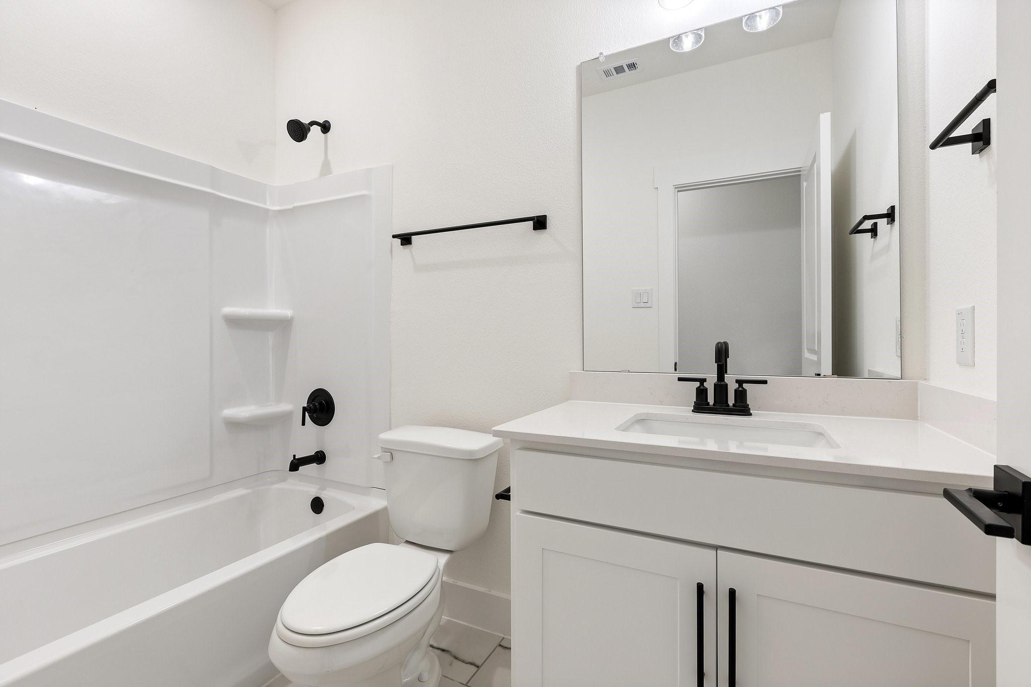Modern bathroom with white vanity, quartz countertop, and matte black fixtures in The Rockford C plan, Josephine, Texas.