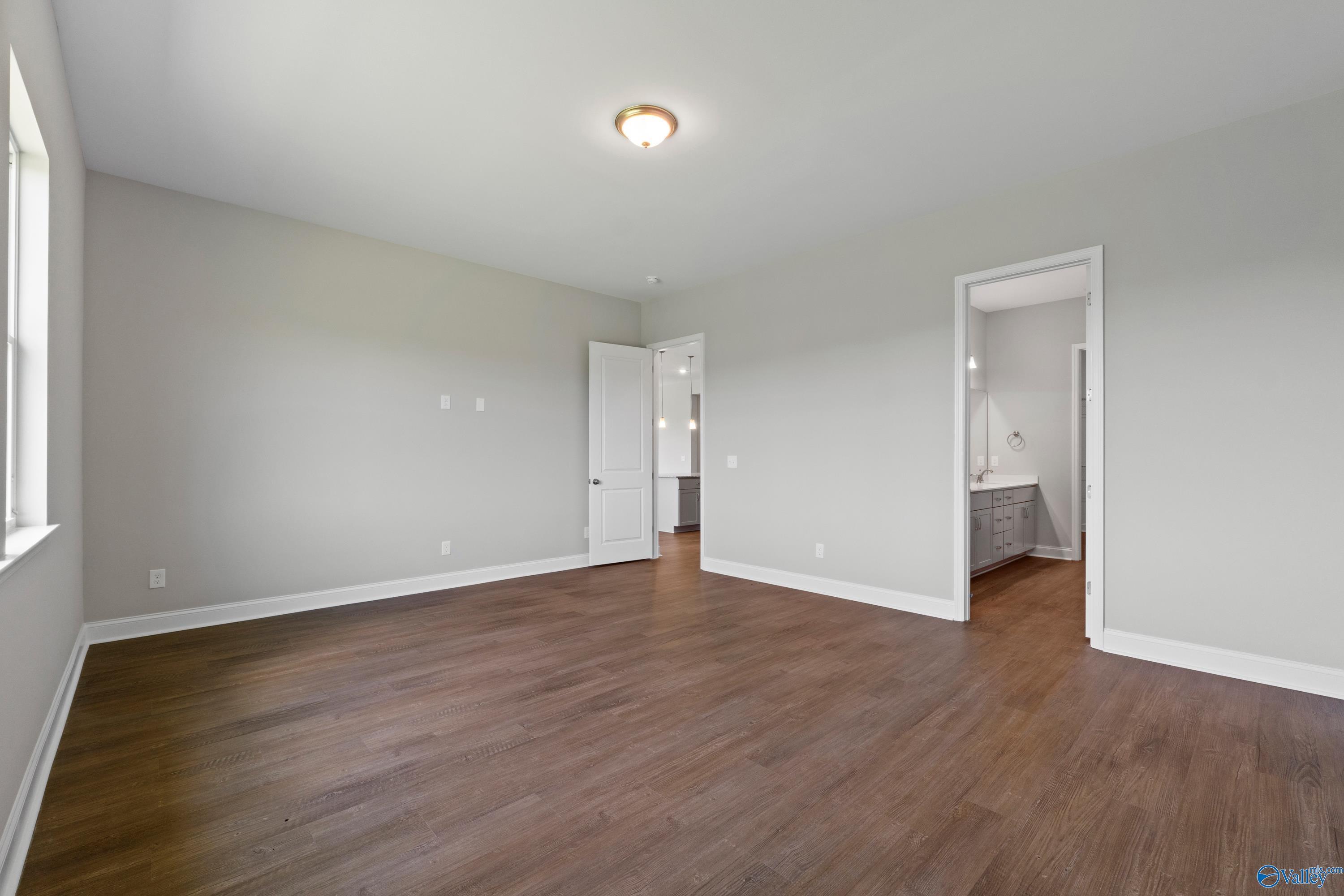 Spacious bedroom with hardwood floors, gray walls, and en-suite bathroom in 4-bedroom The Arcadia B home, Huntsville, Alabama