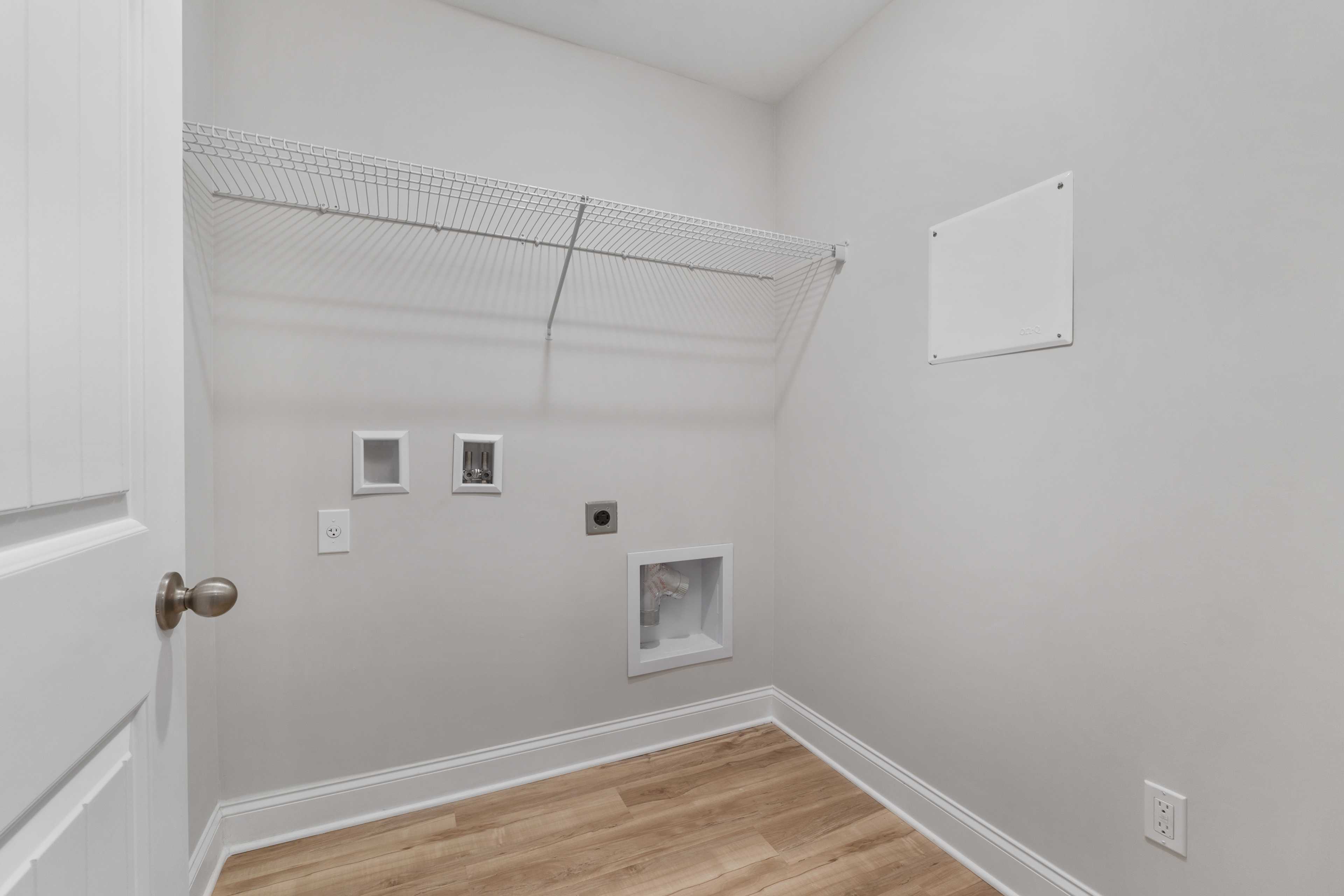Spacious laundry room at Collins Lane in Meridianville, Alabama with wire shelving, washer dryer hookups and hardwood floors