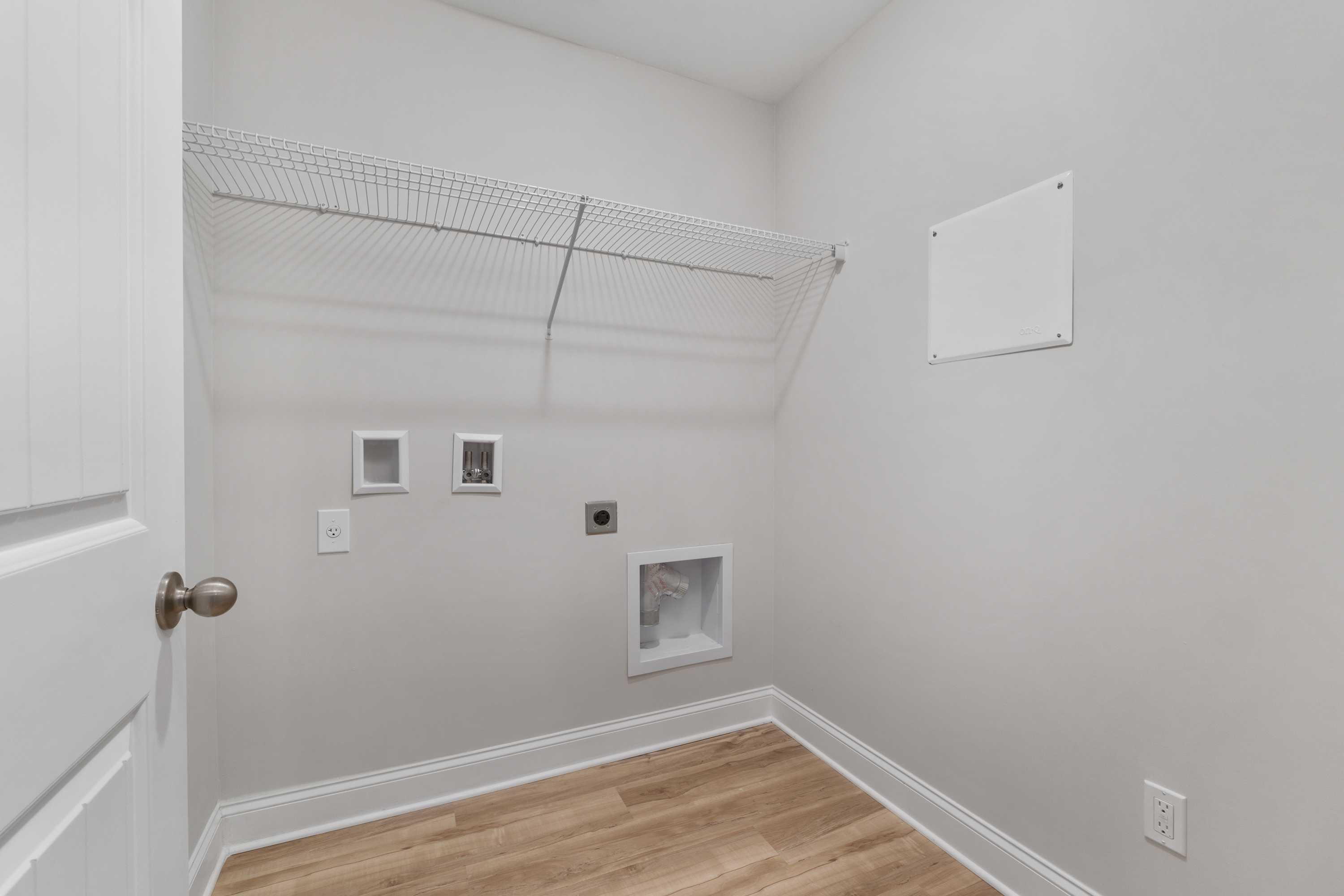 Spacious laundry room at Collins Lane in Meridianville, Alabama with wire shelving, washer dryer hookups and hardwood floors