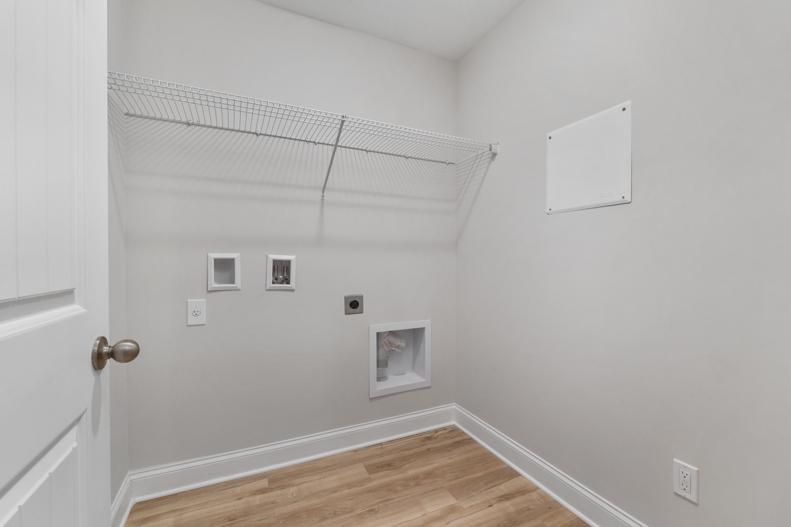 Spacious laundry room at Collins Lane in Meridianville, Alabama with wire shelving, washer dryer hookups and hardwood floors