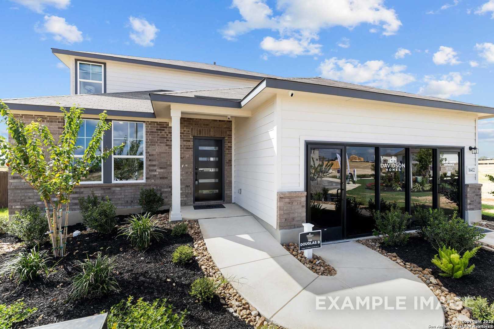Modern two-story Davidson Homes Douglas C facade with white siding, brick accents, large windows, landscaped front yard in Elmendorf, Texas