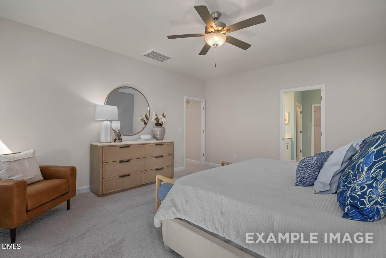 Cozy master bedroom with plush bed, ceiling fan, wooden dresser, and en-suite door in Davidson Homes The Hickory II C, Wake Forest, NC