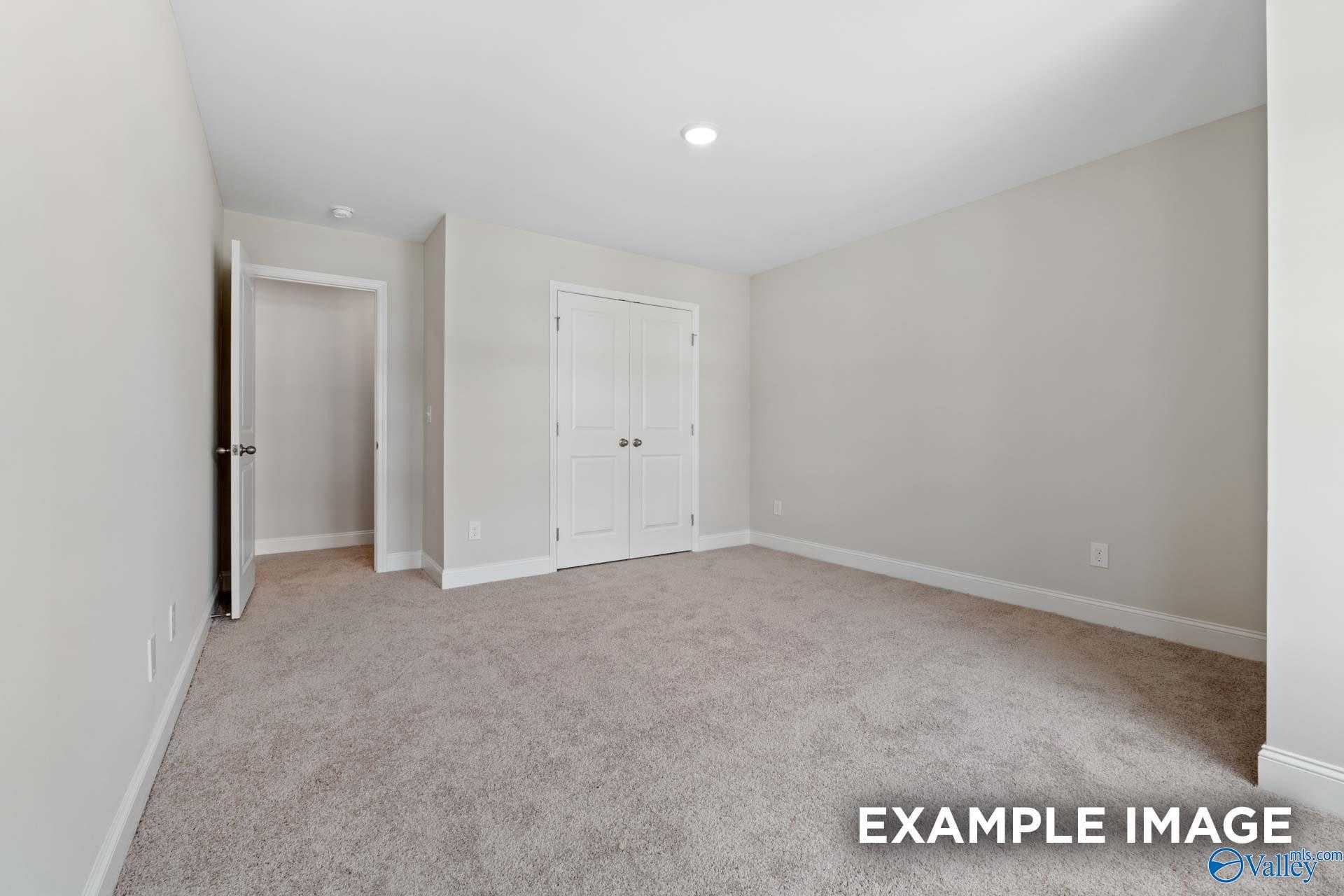 Empty secondary bedroom with neutral walls, double closet doors, and plush carpet in Davidson Homes The Camden, Huntsville, Alabama