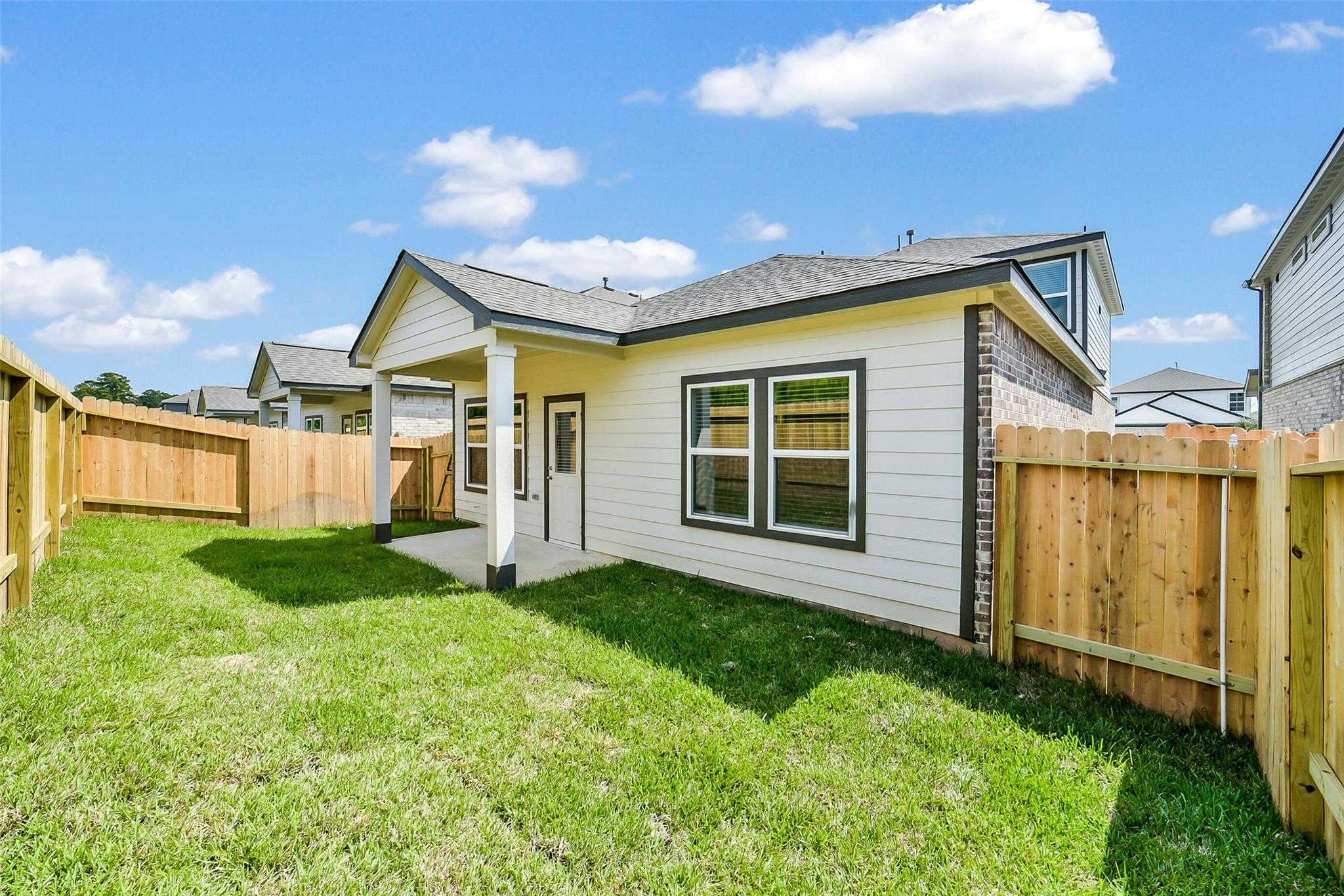 Backyard patio with wooden fence and lush green lawn in Davidson Homes The Blanco E, 4-bedroom home, Magnolia, Texas