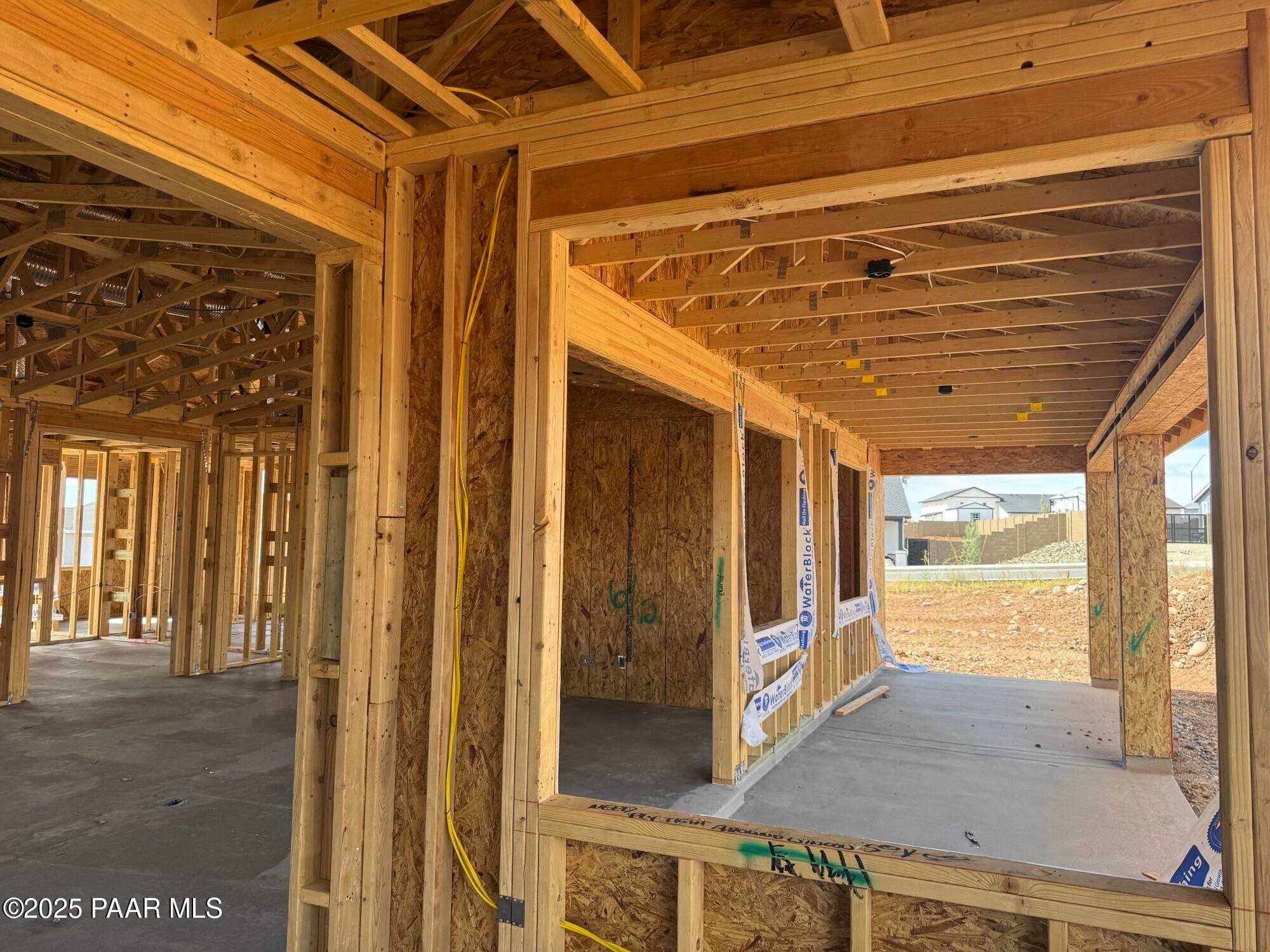 Framed covered back patio with wooden studs, beams, and wiring in Evermore Homes The Monarch B, Prescott Valley, Arizona