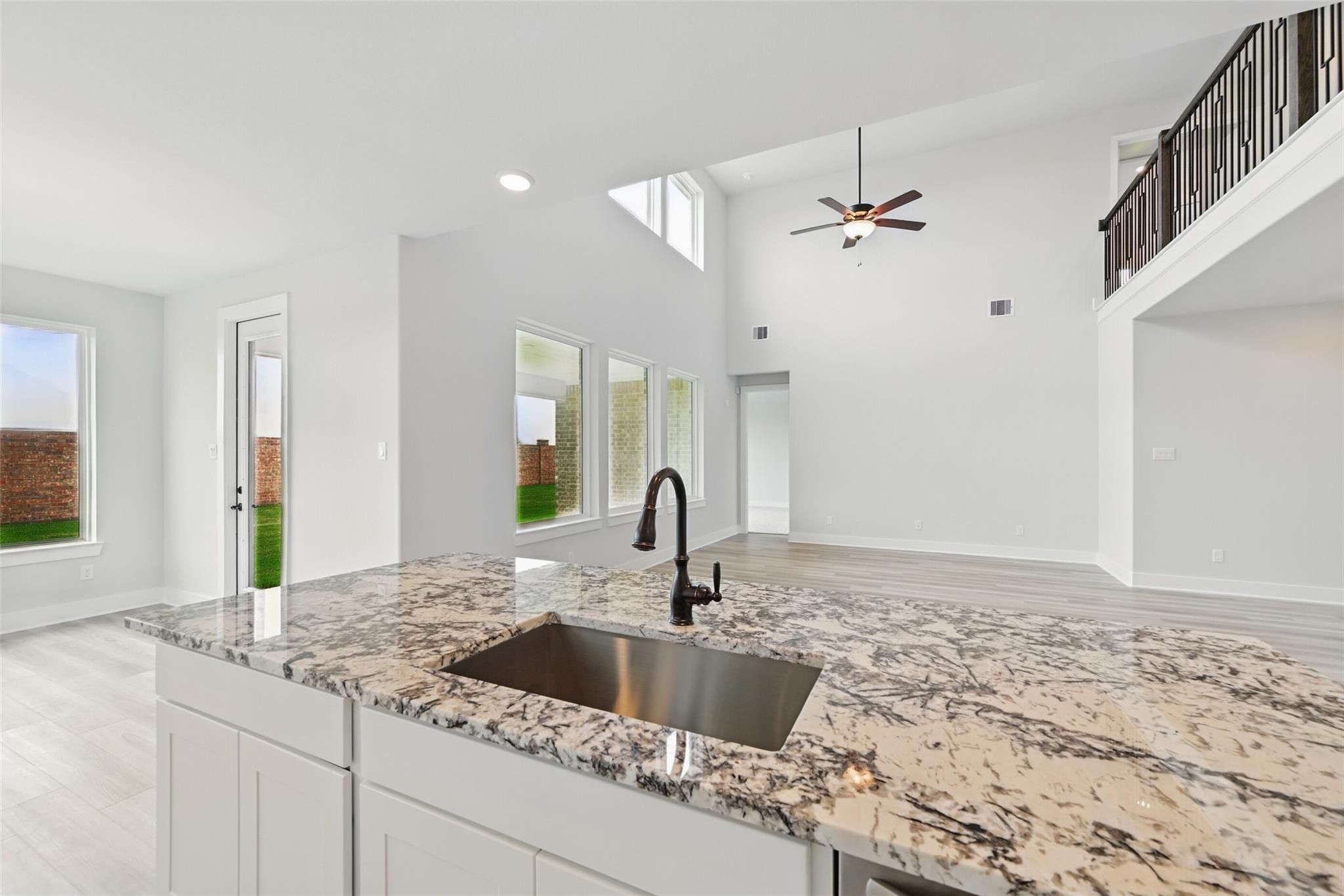 Modern open-concept kitchen with granite island, farmhouse sink, and ceiling fan in 4-bedroom Davidson Homes The Victoria C, Lago Mar, Texas City