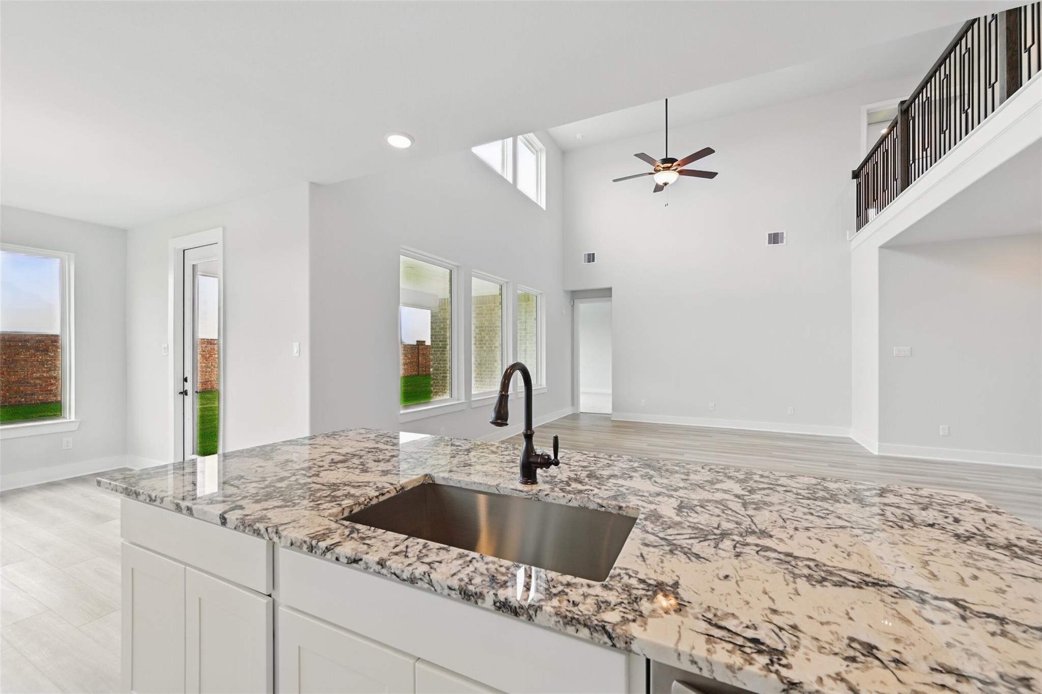 Modern open-concept kitchen with granite island, farmhouse sink, and ceiling fan in 4-bedroom Davidson Homes The Victoria C, Lago Mar, Texas City