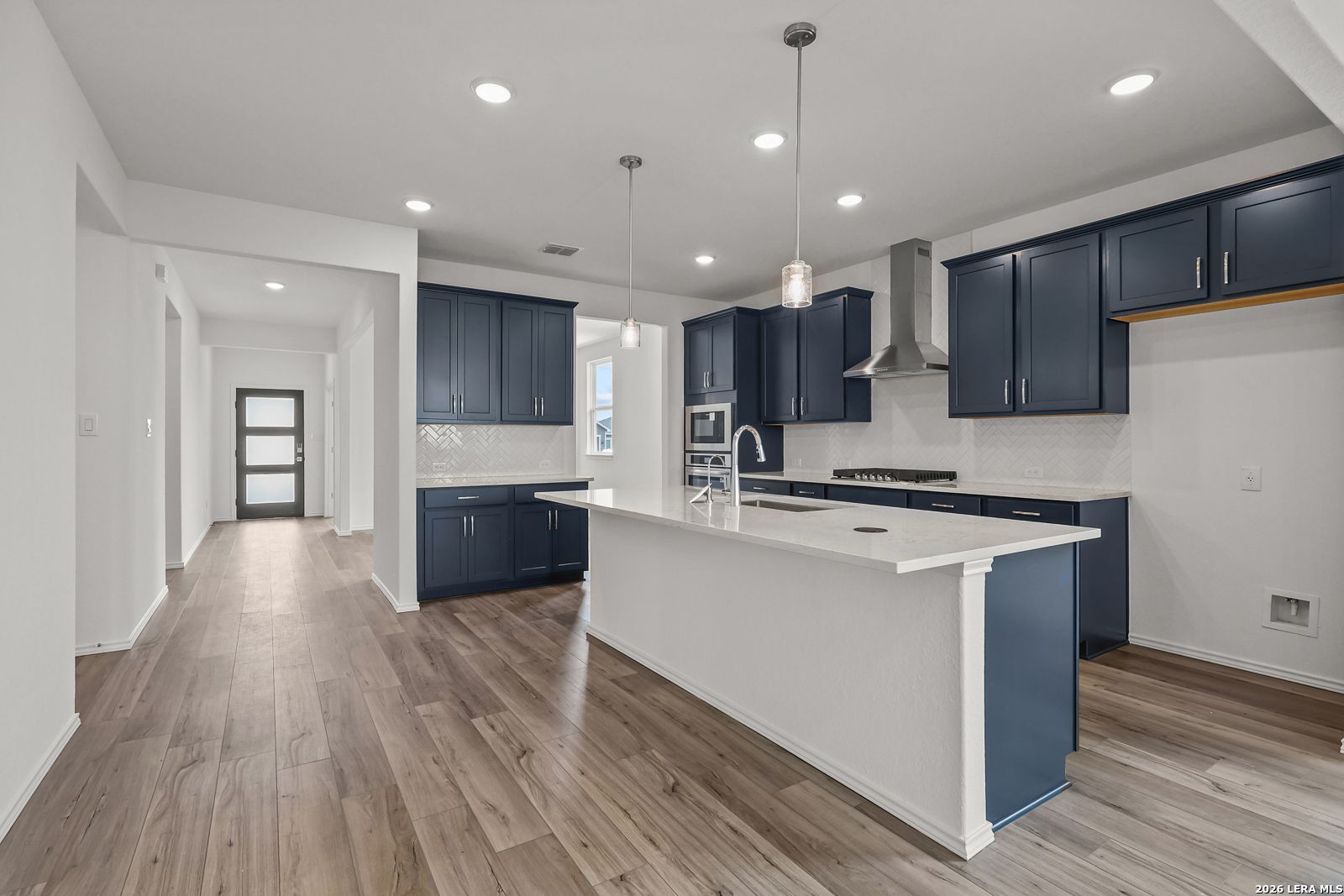 Modern navy blue kitchen cabinets, white quartz island, stainless appliances in Davidson Homes The Glenwood E, Elmendorf, Texas