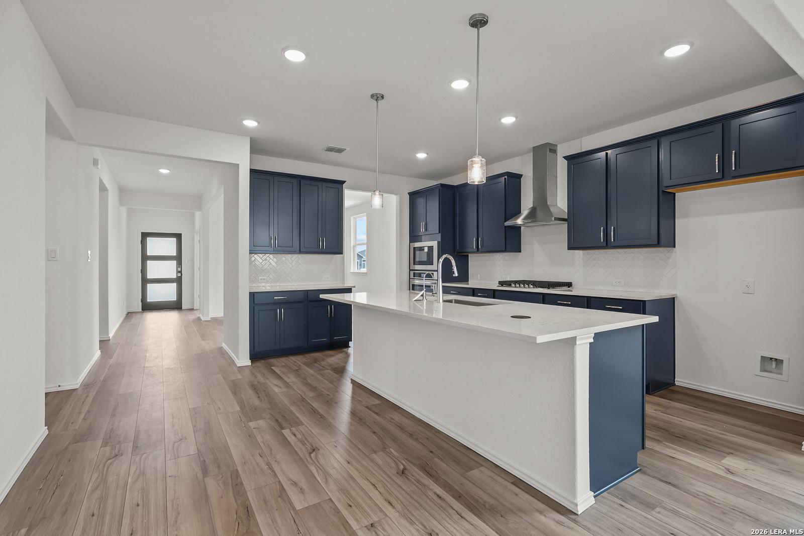 Modern navy blue kitchen cabinets, white quartz island, stainless appliances in Davidson Homes The Glenwood E, Elmendorf, Texas