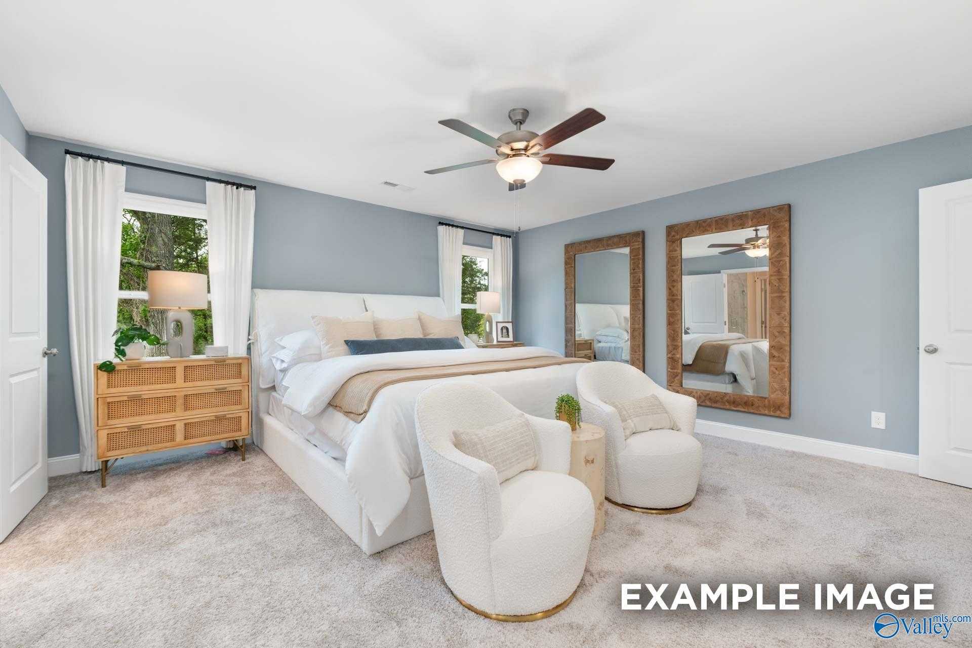 Elegant master bedroom with king bed, light blue walls, ceiling fan, armchairs, mirrors in Davidson Homes The Camden B, Huntsville, Alabama