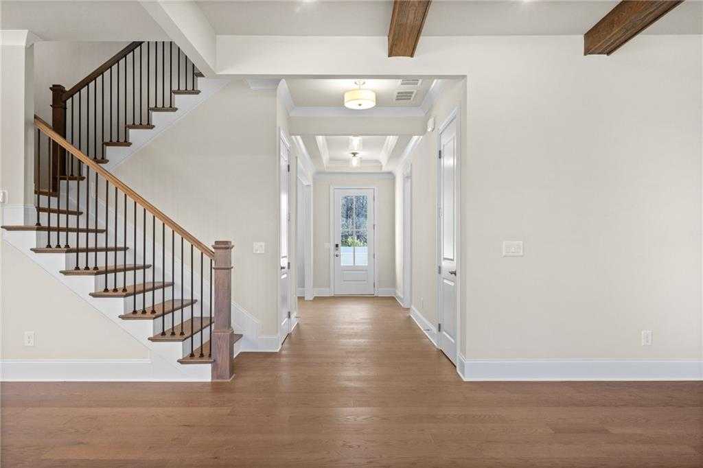 Grand wooden staircase in open foyer with beamed ceiling, hardwood floors, and hallway doors in Davidson Homes The Arlington A, East Cobb, Georgia