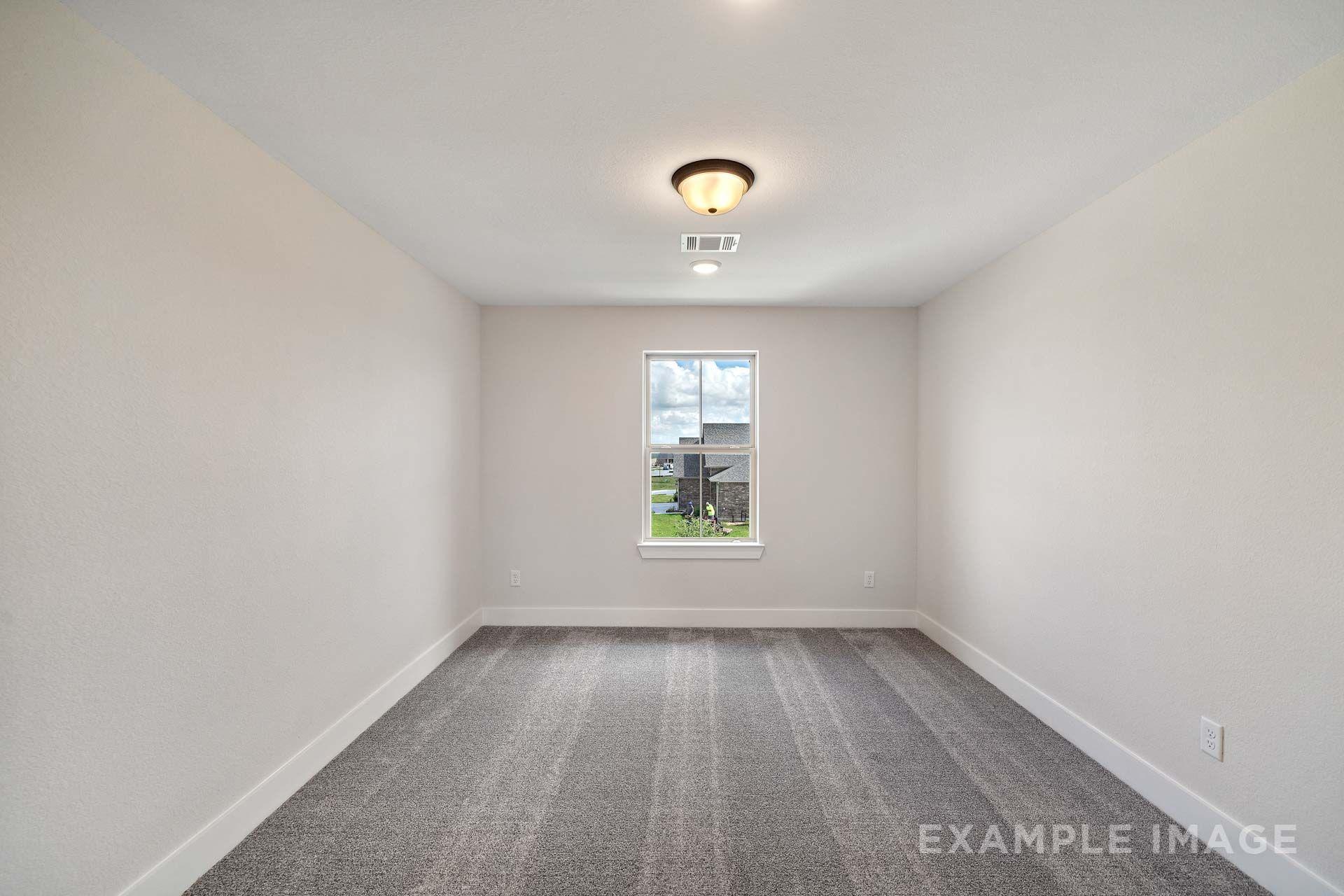 Spacious bedroom in The Victoria by Davidson Homes featuring gray carpet, neutral walls, and natural light from window overlooking Texas City neighborhood