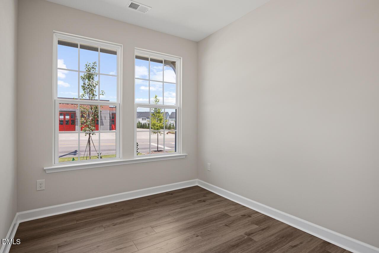 Bright bedroom with wood-style flooring and large windows in The Alexander C floor plan, Forestville Yard, Knightdale, NC.