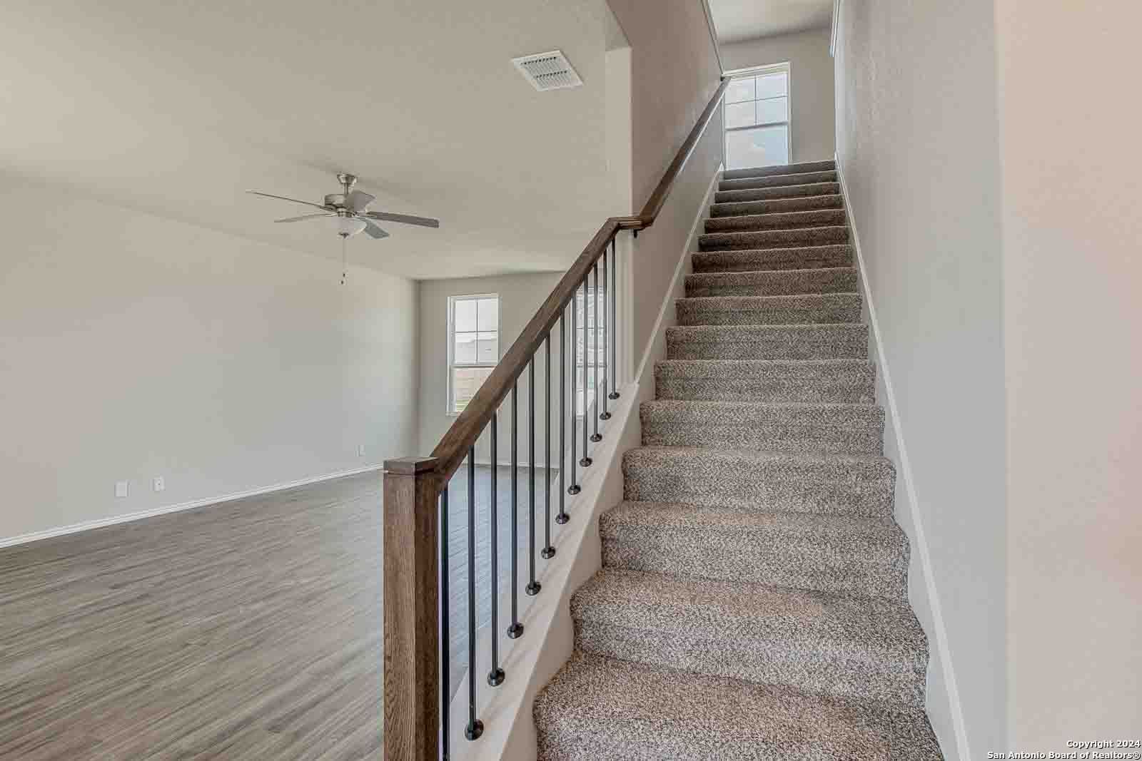 Elegant carpeted staircase with wrought iron balusters in open two-story foyer, Davidson Homes The Murray H in Seguin, Texas