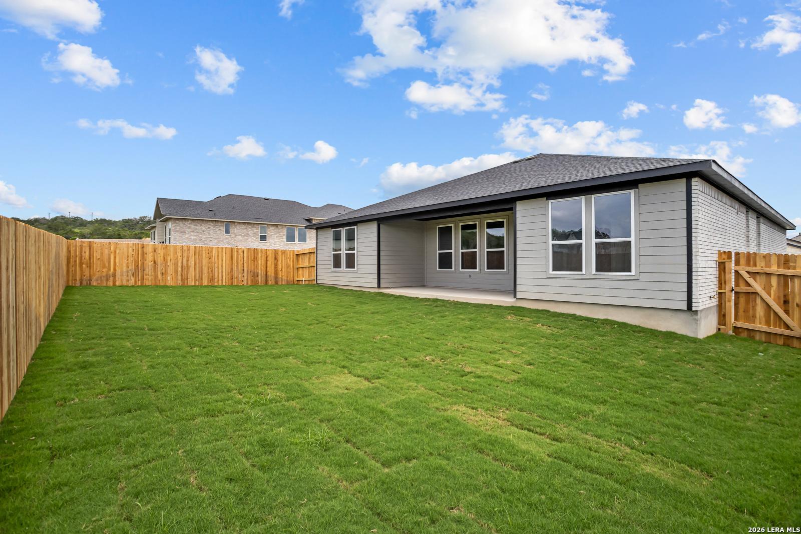 Large fenced backyard with green lawn at The Lanier G floor plan home in The Reserve at Potranco Oaks, Castroville, Texas.