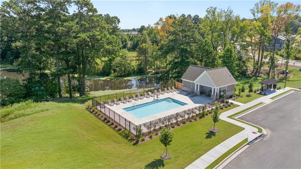 Community pool with cabana and lounge chairs beside scenic pond in Lake Shore neighborhood, Davidson Homes, Winder, Georgia