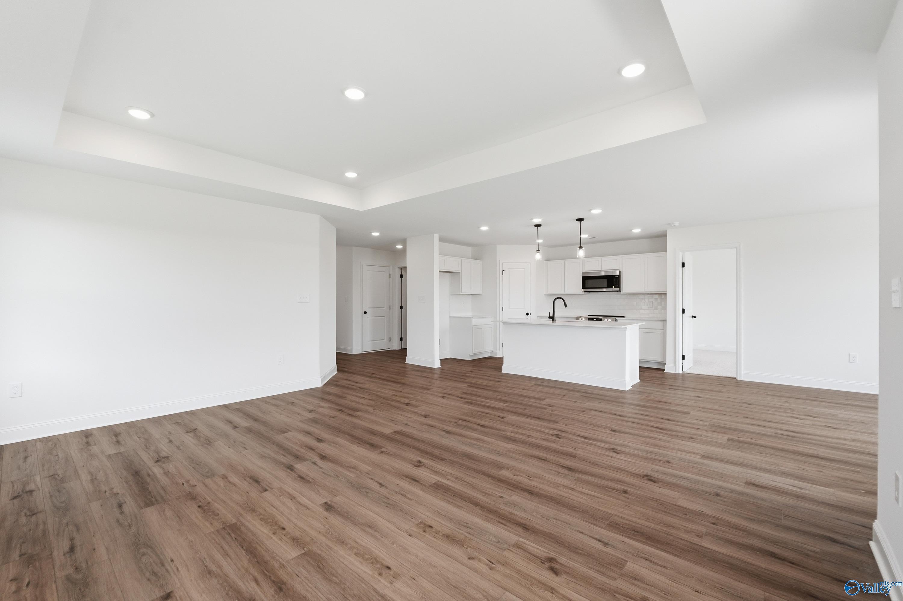 Open-concept living room and kitchen with tray ceilings in The Franklin floor plan at Heritage Lakes, New Market, AL.
