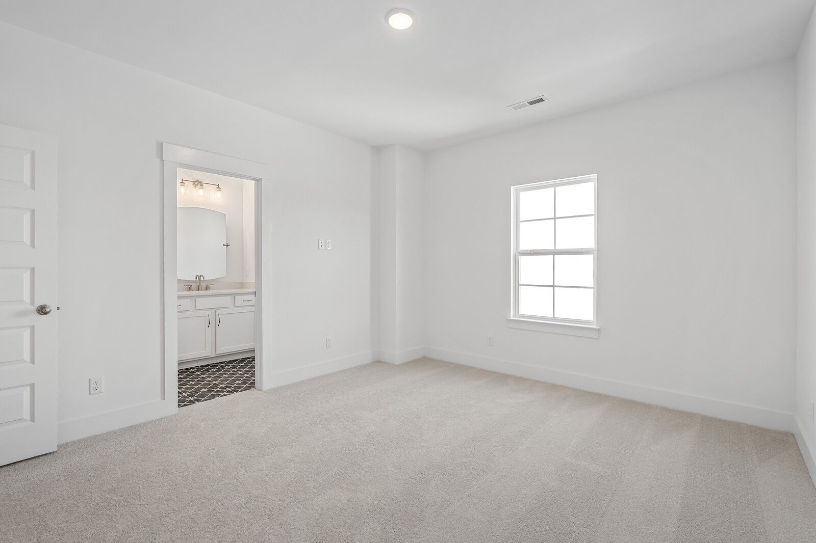 Bright bedroom with en-suite bathroom, white vanity, and tiled floor in Davidson Homes The Hawkins, Murfreesboro, TN