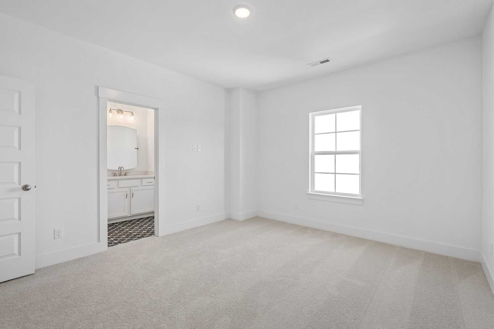 Bright bedroom with en-suite bathroom, white vanity, and tiled floor in Davidson Homes The Hawkins, Murfreesboro, TN
