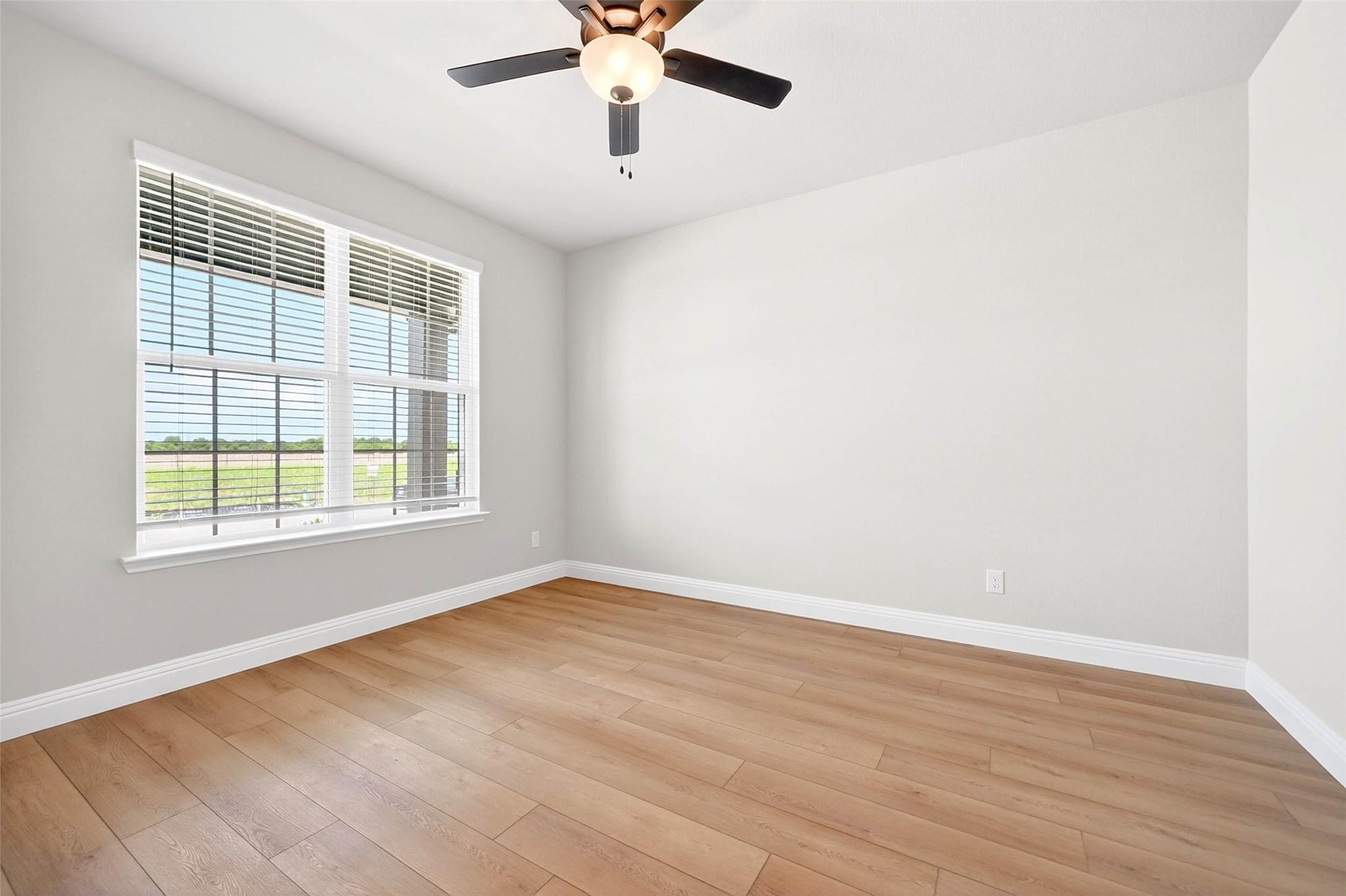 Bright secondary bedroom with wood-look flooring and ceiling fan in The Holly C floor plan at Parks at Foster Crossing.