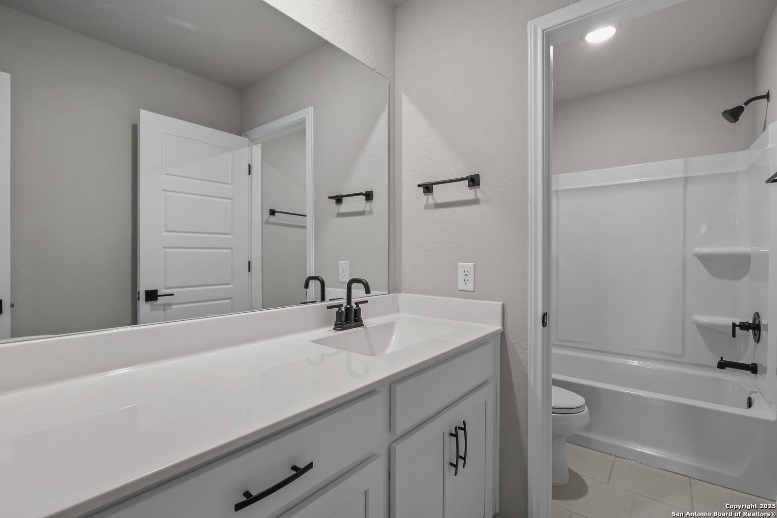 Modern secondary bathroom with double vanity, frameless shower, soaking tub in Davidson Homes The Brazos C, San Antonio